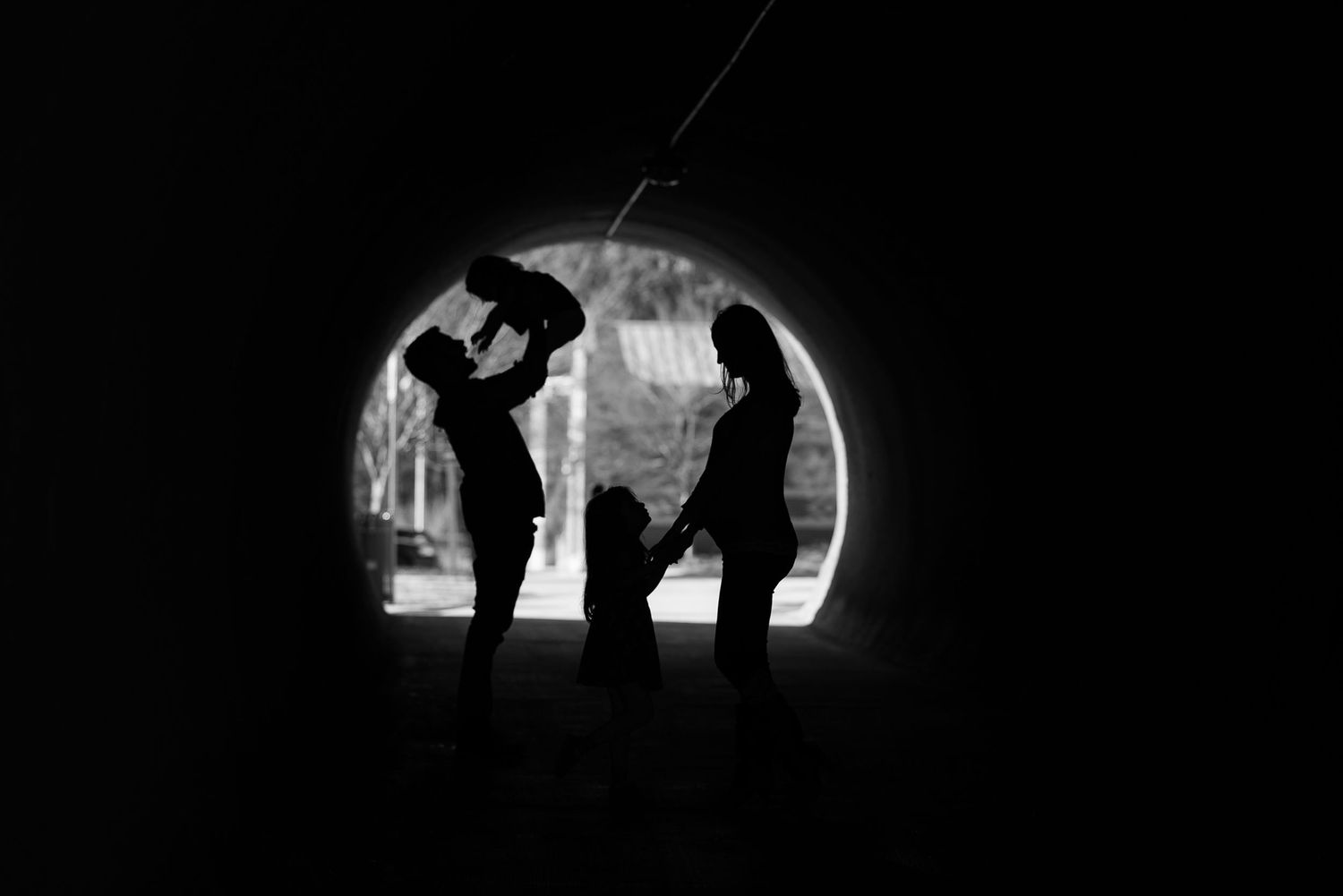Artistic silhouette photography in dark tunnel showcasing dramatic shadows and figures.