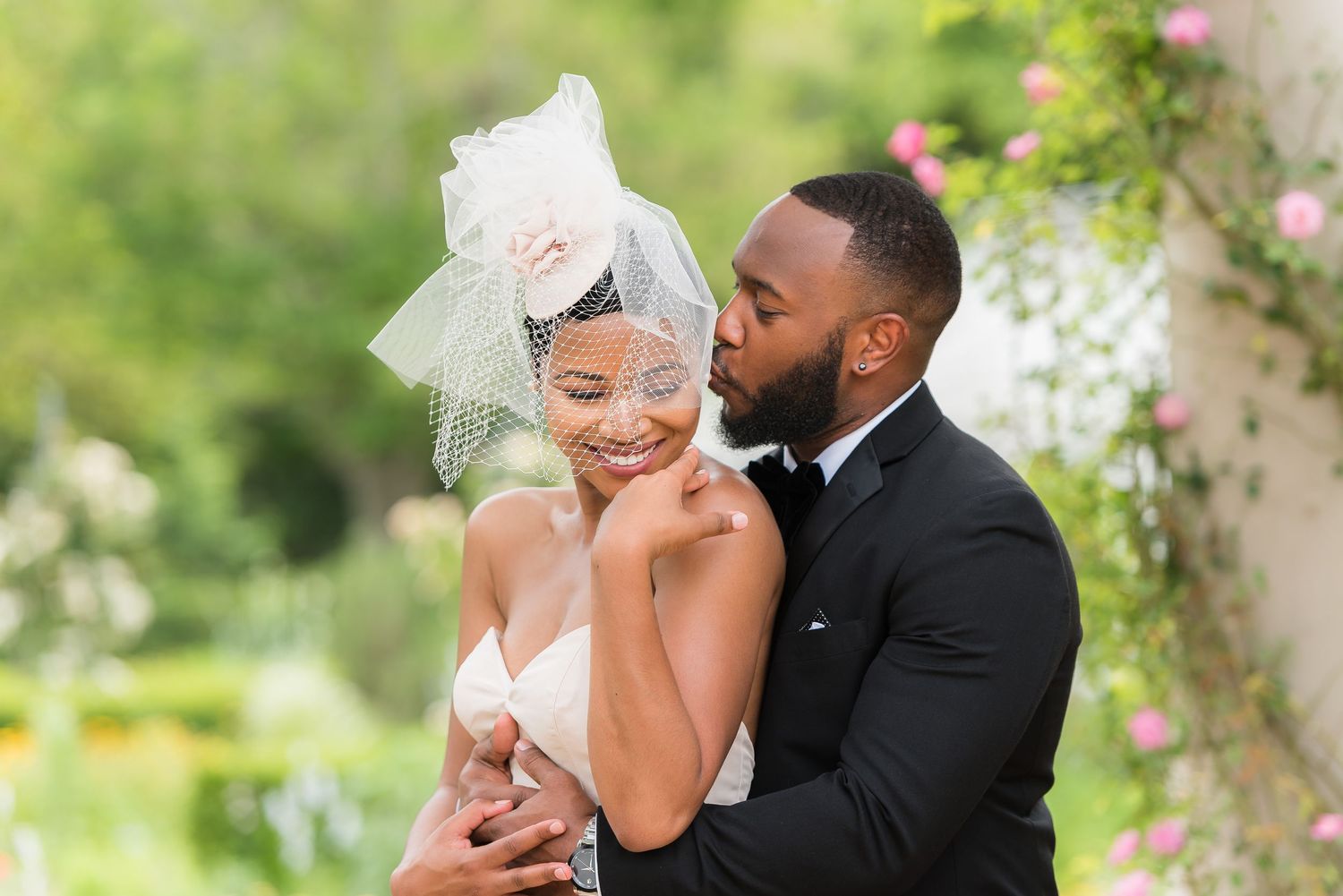 A romantic wedding portrait captured in a lush green garden setting.