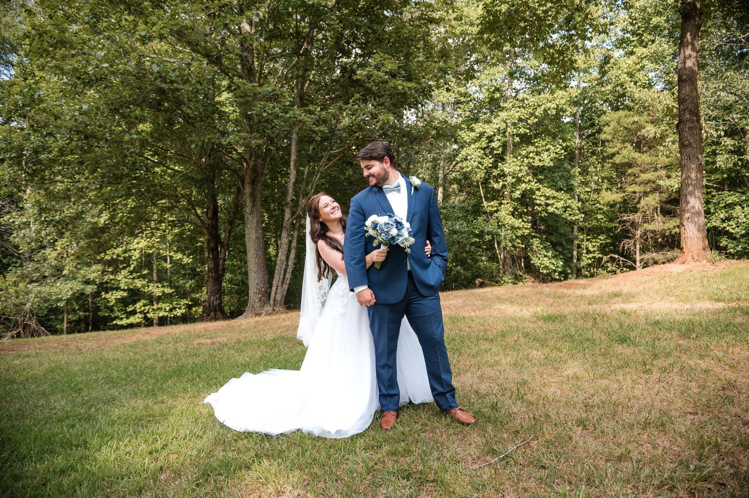 A serene outdoor wedding scene with trees and natural landscaping in the background.