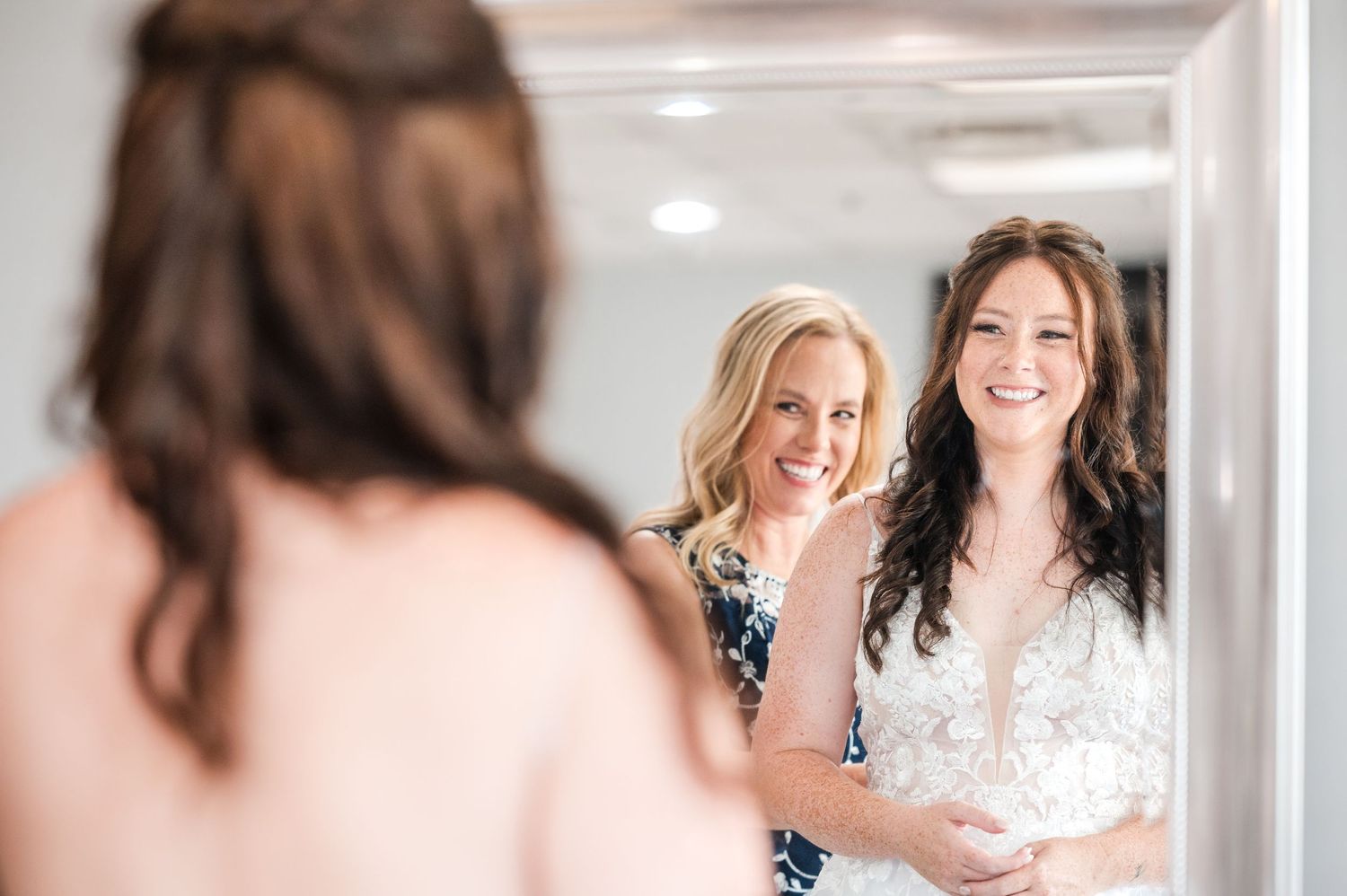 A joyful bridal preparation scene with supportive friends in a sunlit room.