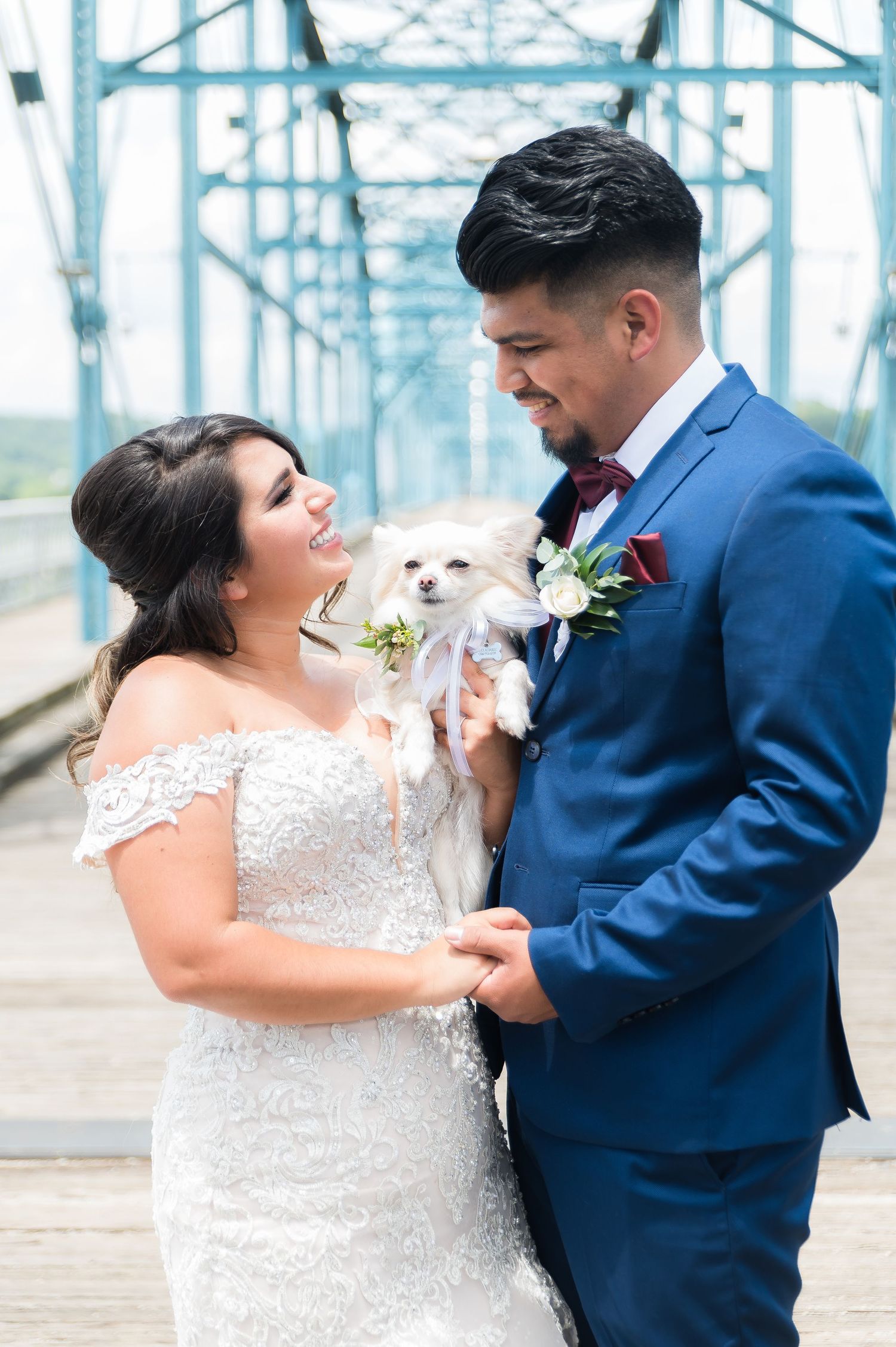 Romantic wedding couple dancing and embracing under a blue bridge wearing navy and white.