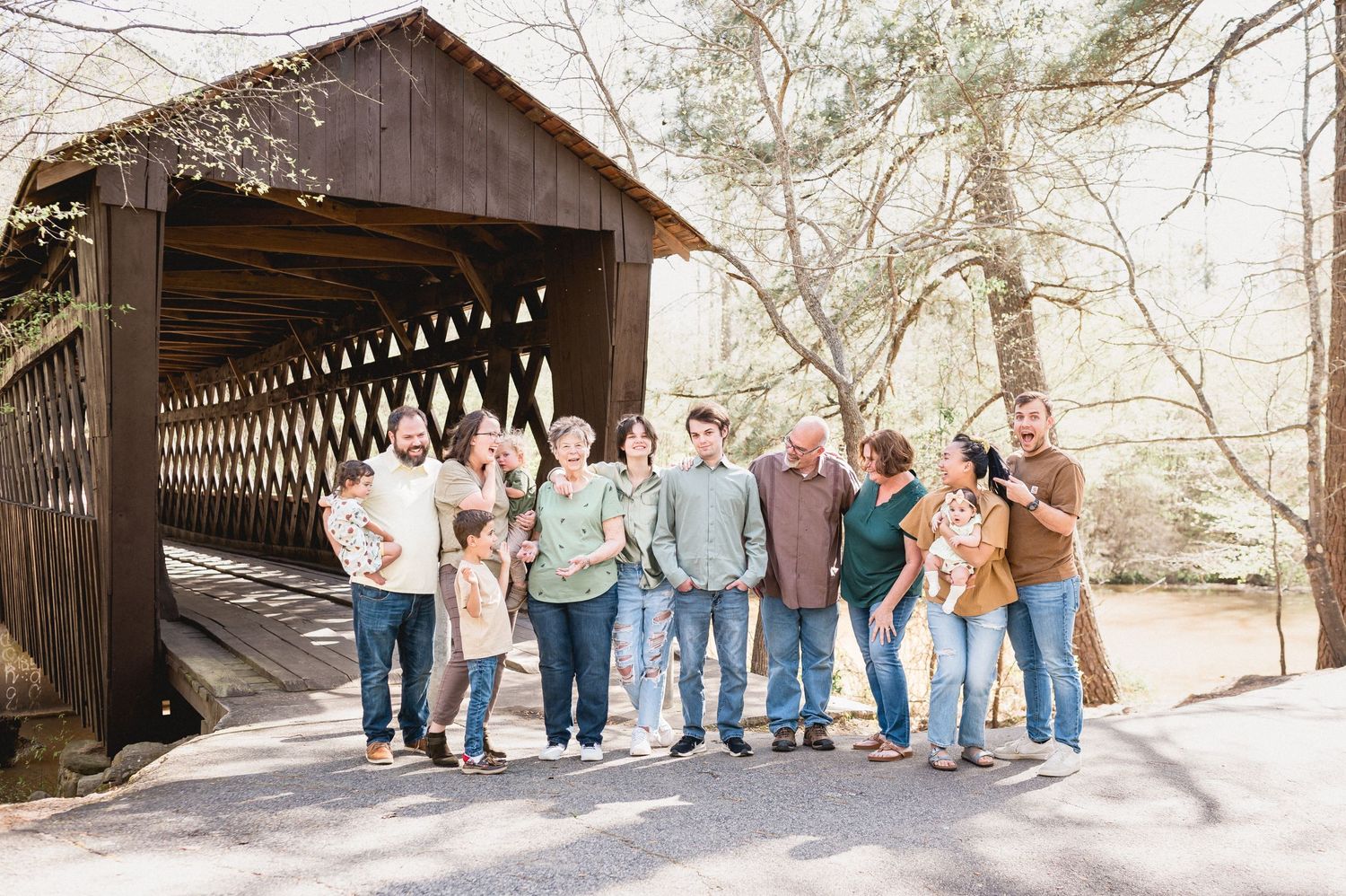 Group photo of people standing together in front of a rustic covered bridge.
