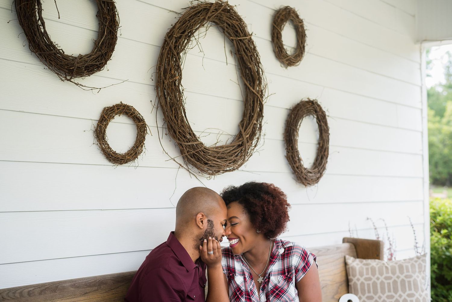 A couple shares an intimate moment on a couch with rustic twig wreaths decorating the white wall behind them.