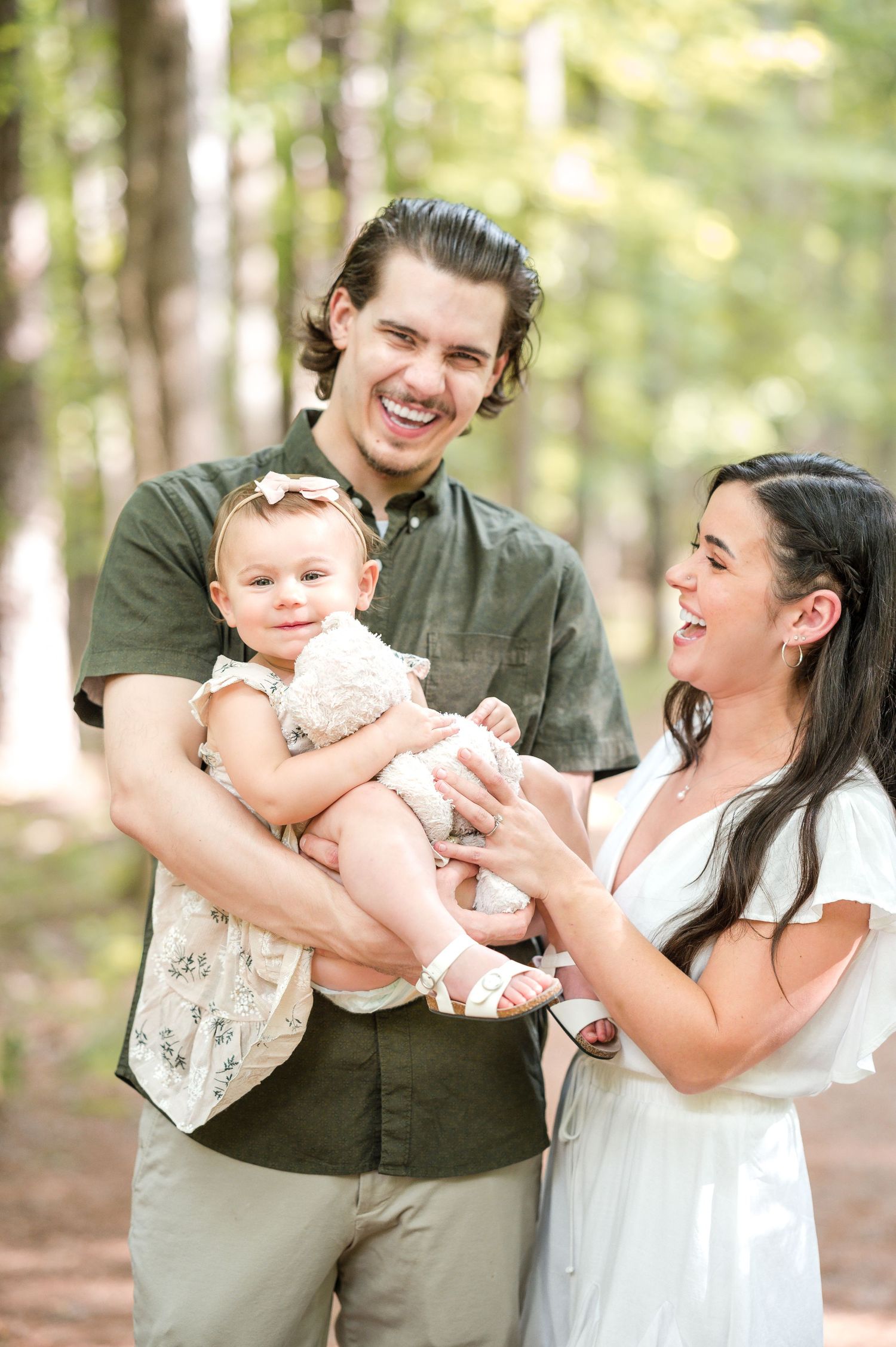 A joyful family moment with a baby captured in a sunny forest setting.