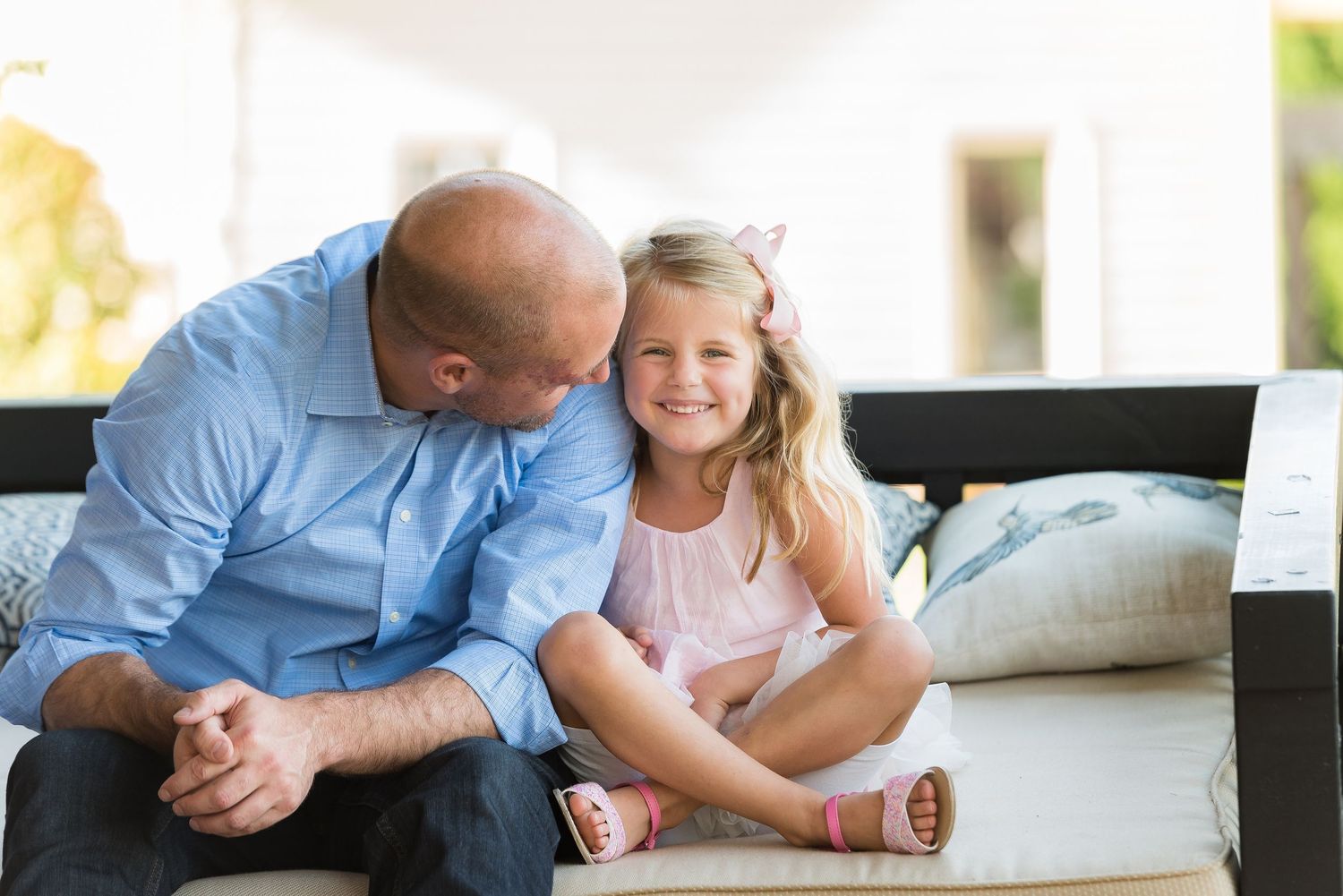 A tender moment shared on a white couch with soft natural lighting.
