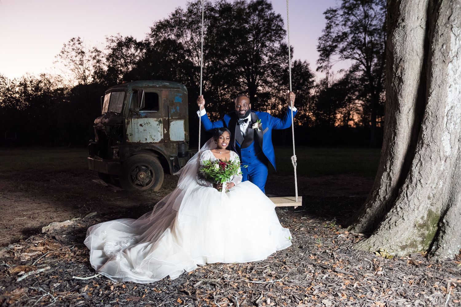 Wedding photos taken at sunset under large trees with dramatic lighting.