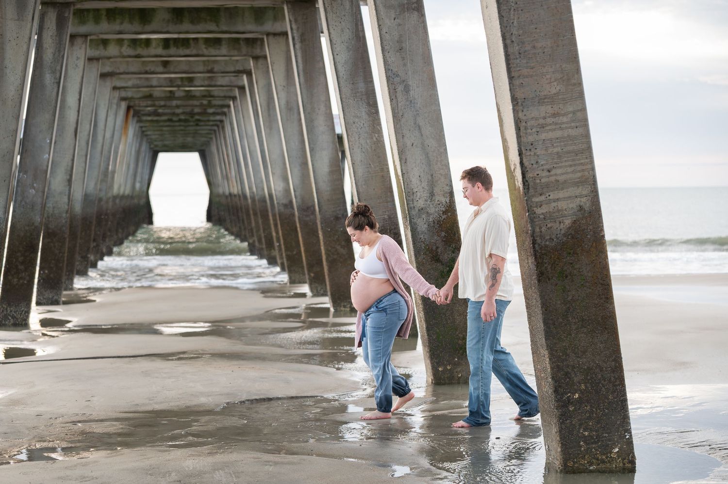 Family moment captured beneath geometric pier structure at the ocean.