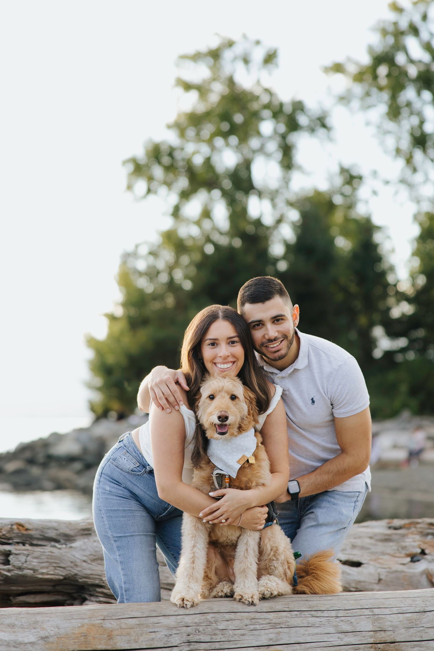 Couple holding hands and hugging dog during engagement session in Seattle