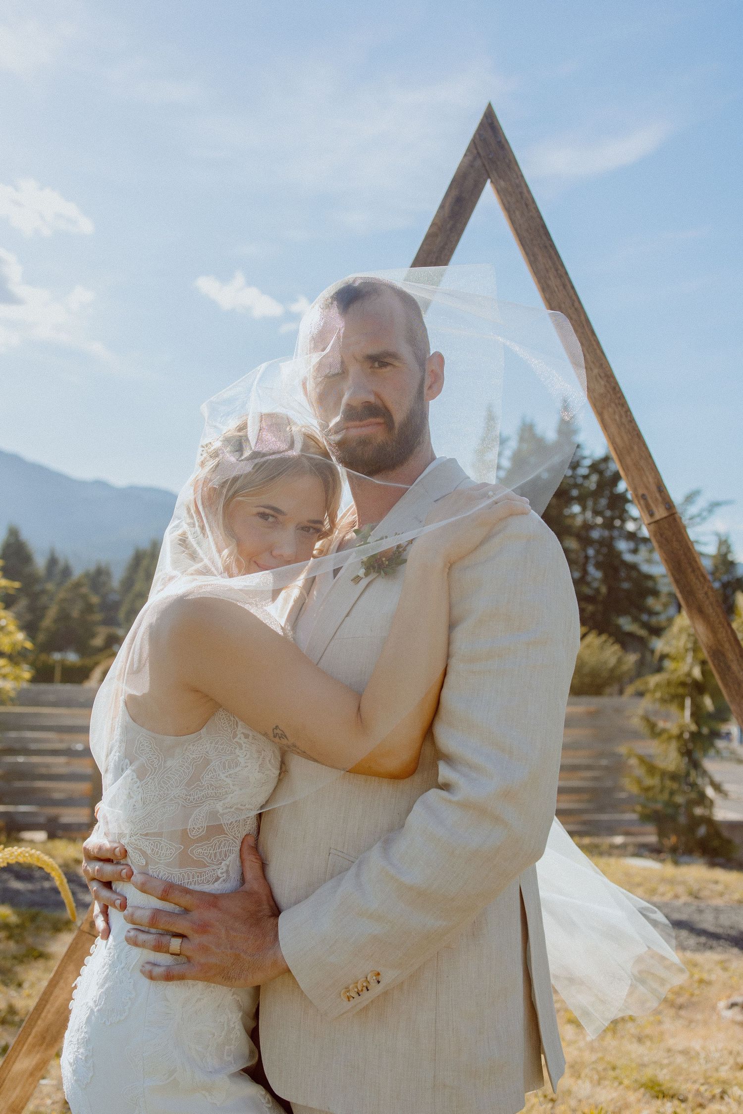 Romantic embrace in rustic outdoor mountain setting with warm sunlight and natural scenery showing a magical wedding moment.