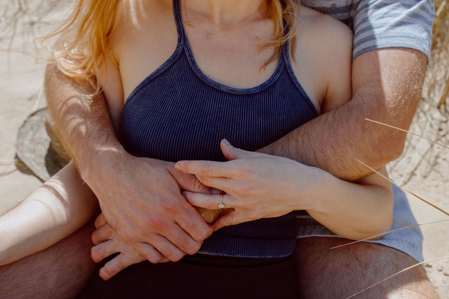 A close-up shot of hands in a tender embrace resting on a lap.
