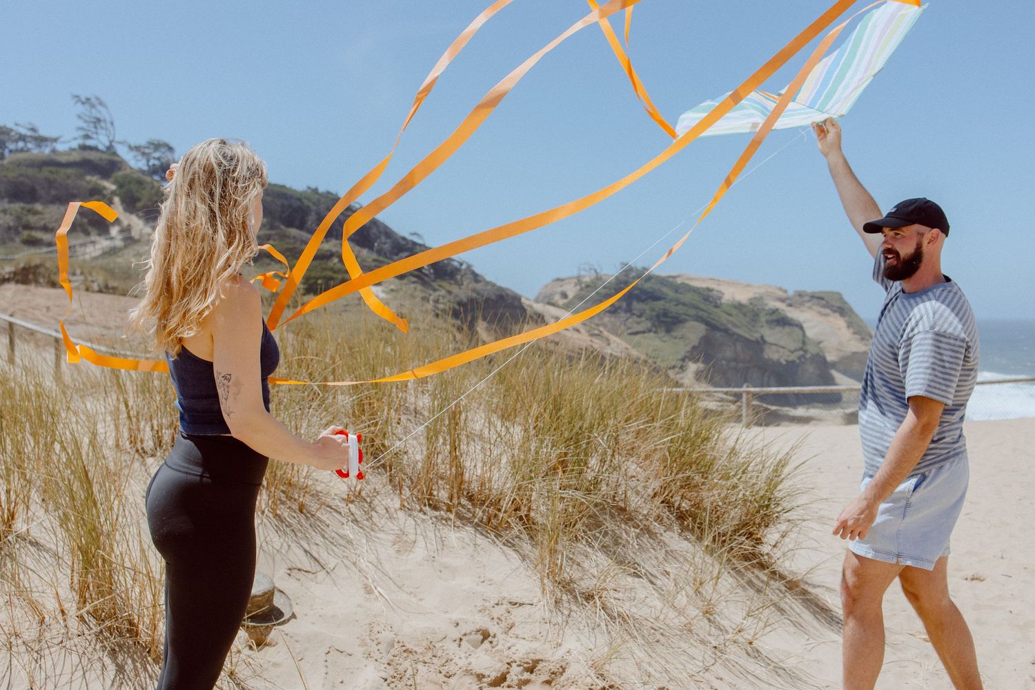 A series of sunny beach engagement photos showing couples walking on sandy dunes with ocean views.