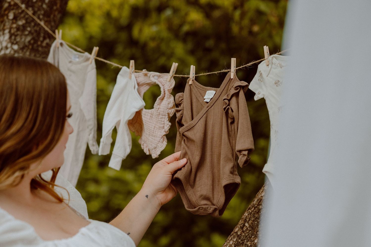Decorative laundry items and vintage-style garments hanging on a clothesline outdoors against a blurred green background.