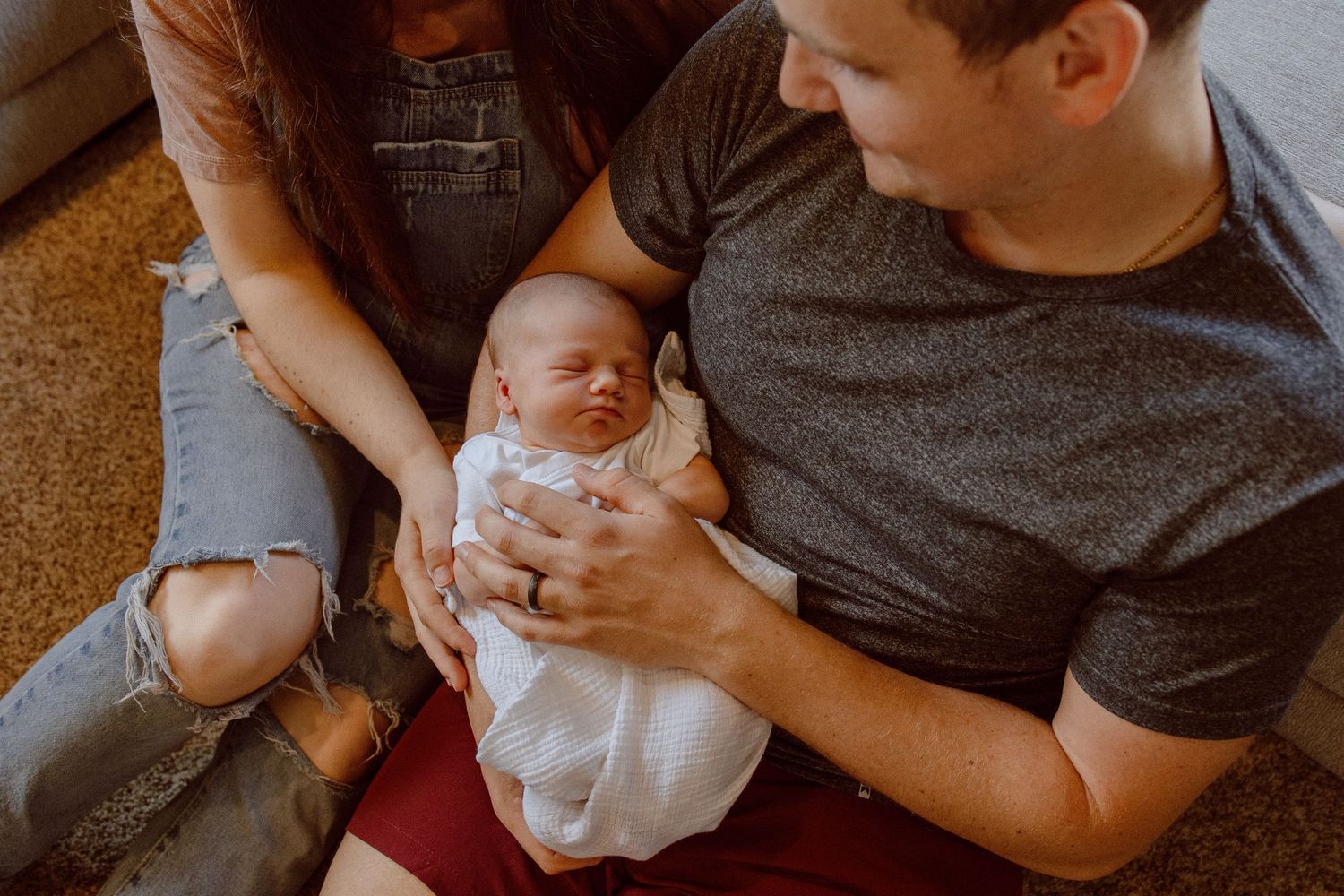 A sequence of photos showing two parents cradling and bonding with their newborn baby wrapped in a white blanket.