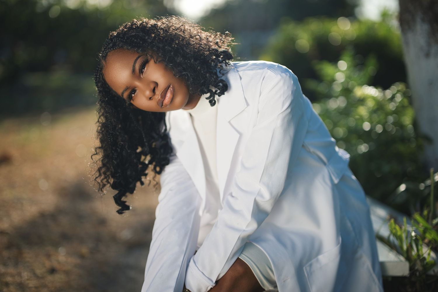 A person in a white shirt walks through a lush garden setting during golden hour sunlight.