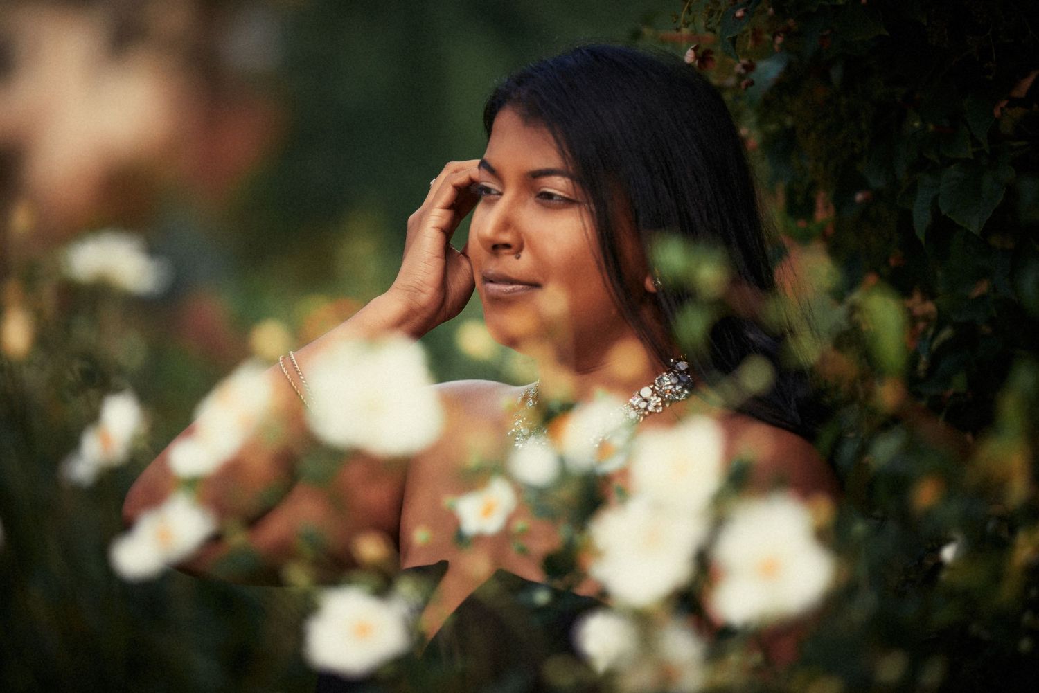 Artistic portrait with bokeh effects and soft lighting among white flowers.