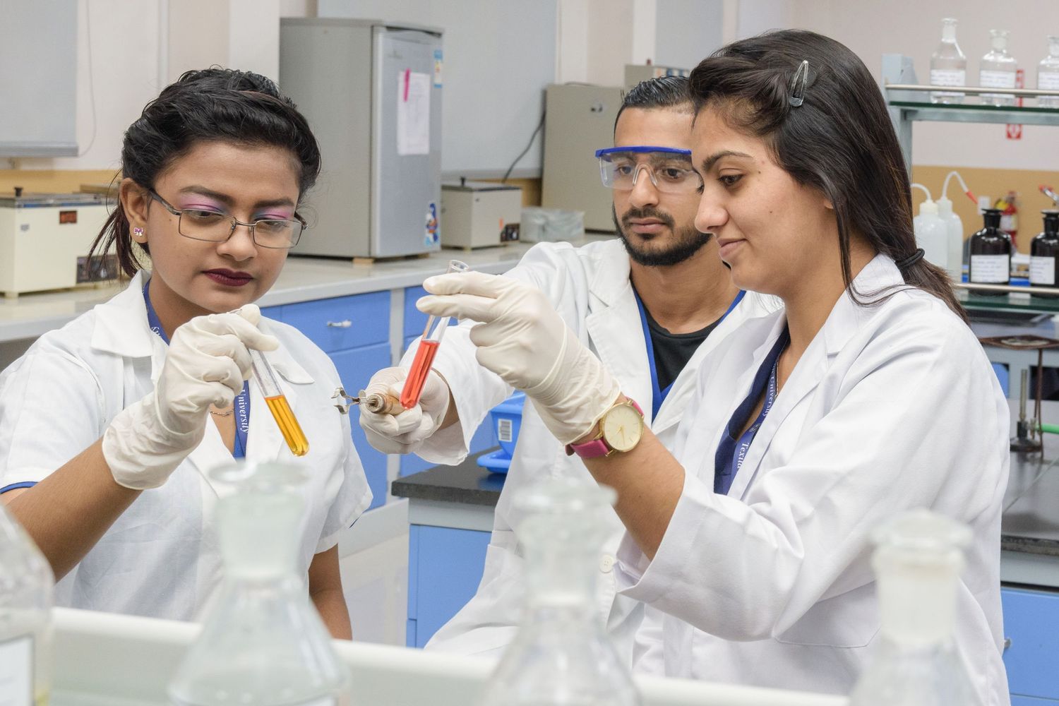 Research team collaborating on laboratory experiments while wearing protective equipment.