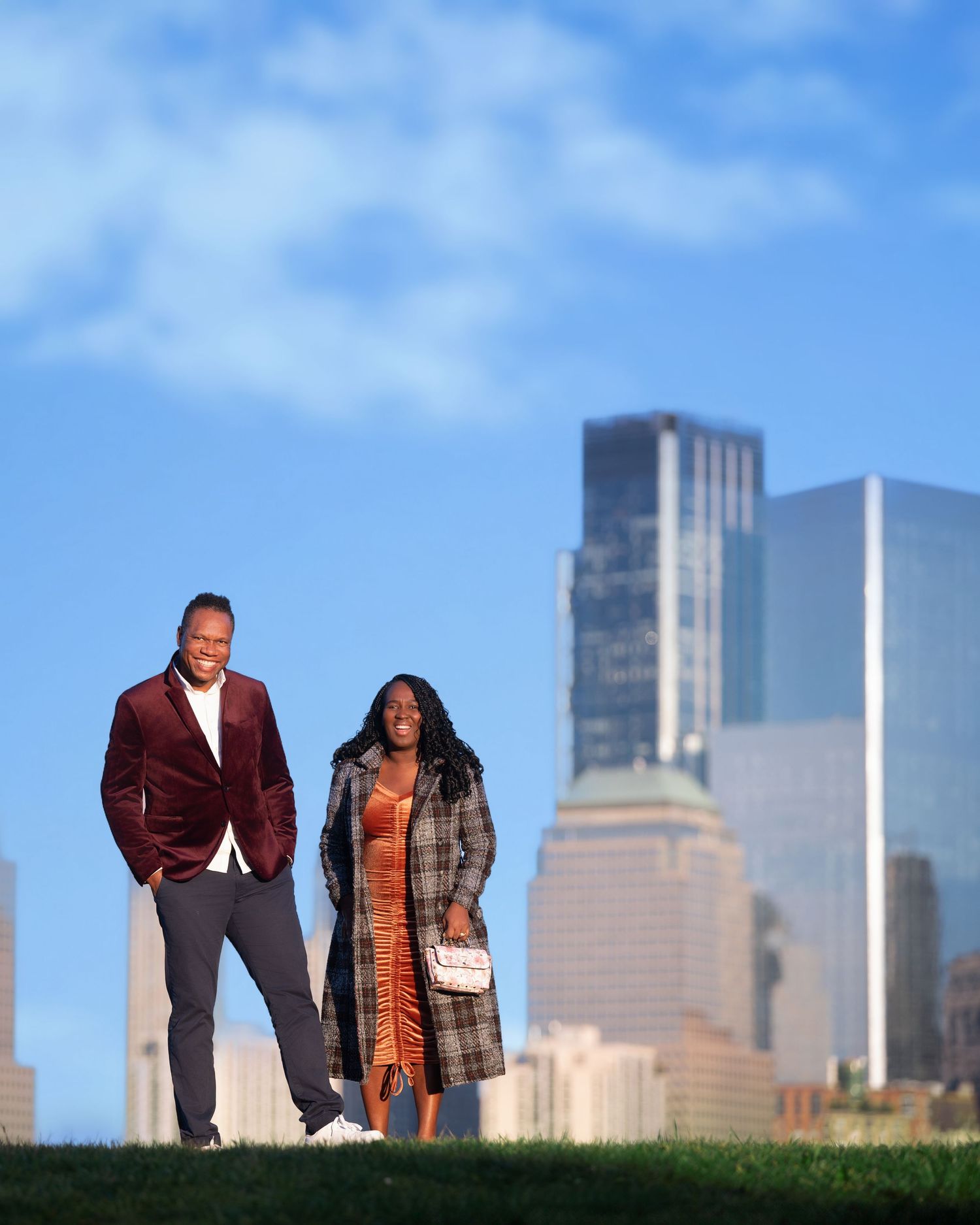 A couple poses together against the Minneapolis skyline on a grassy hill during a romantic outdoor photoshoot.