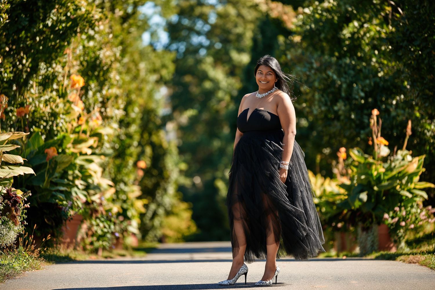 Dramatic outdoor photo shoot on a tree-lined path in natural lighting.