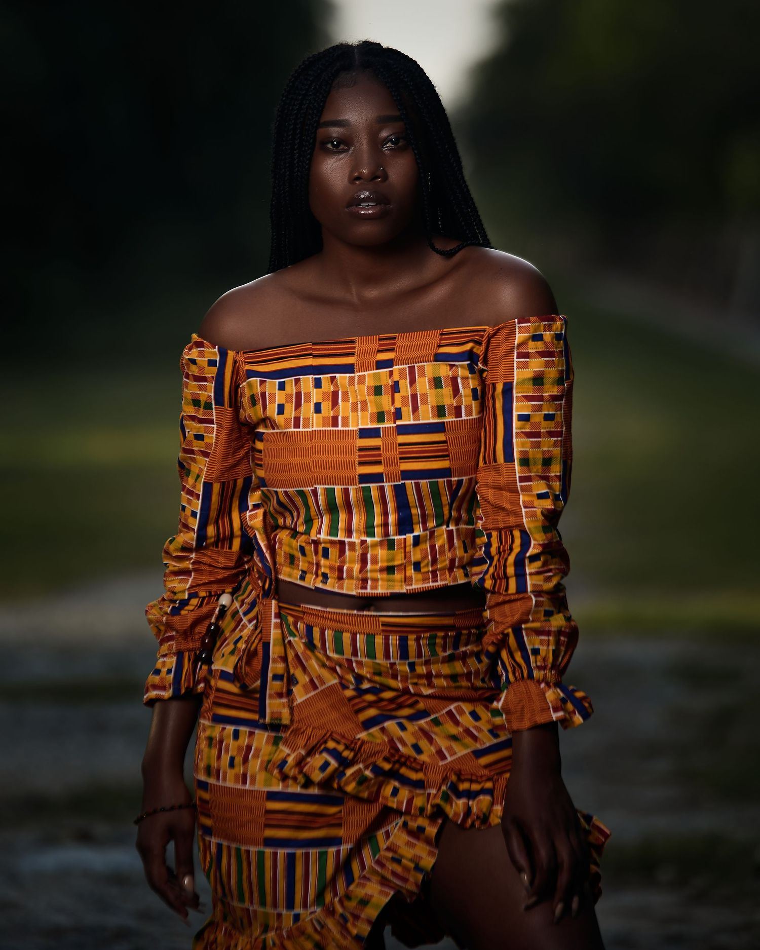 Fashion portrait showcasing a vibrant orange African print off-shoulder dress.