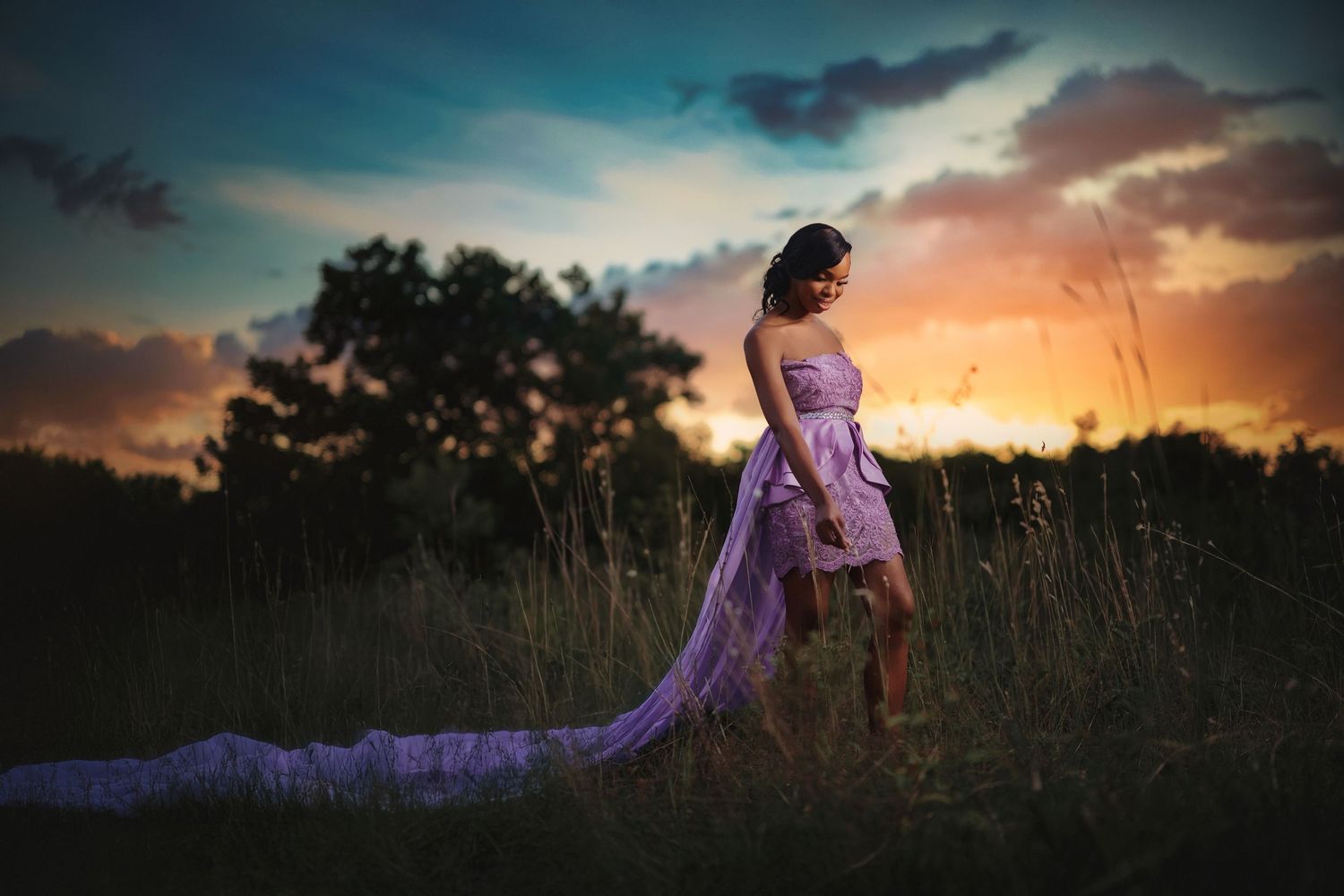 Purple gown creates ethereal silhouette against dramatic sunset sky.