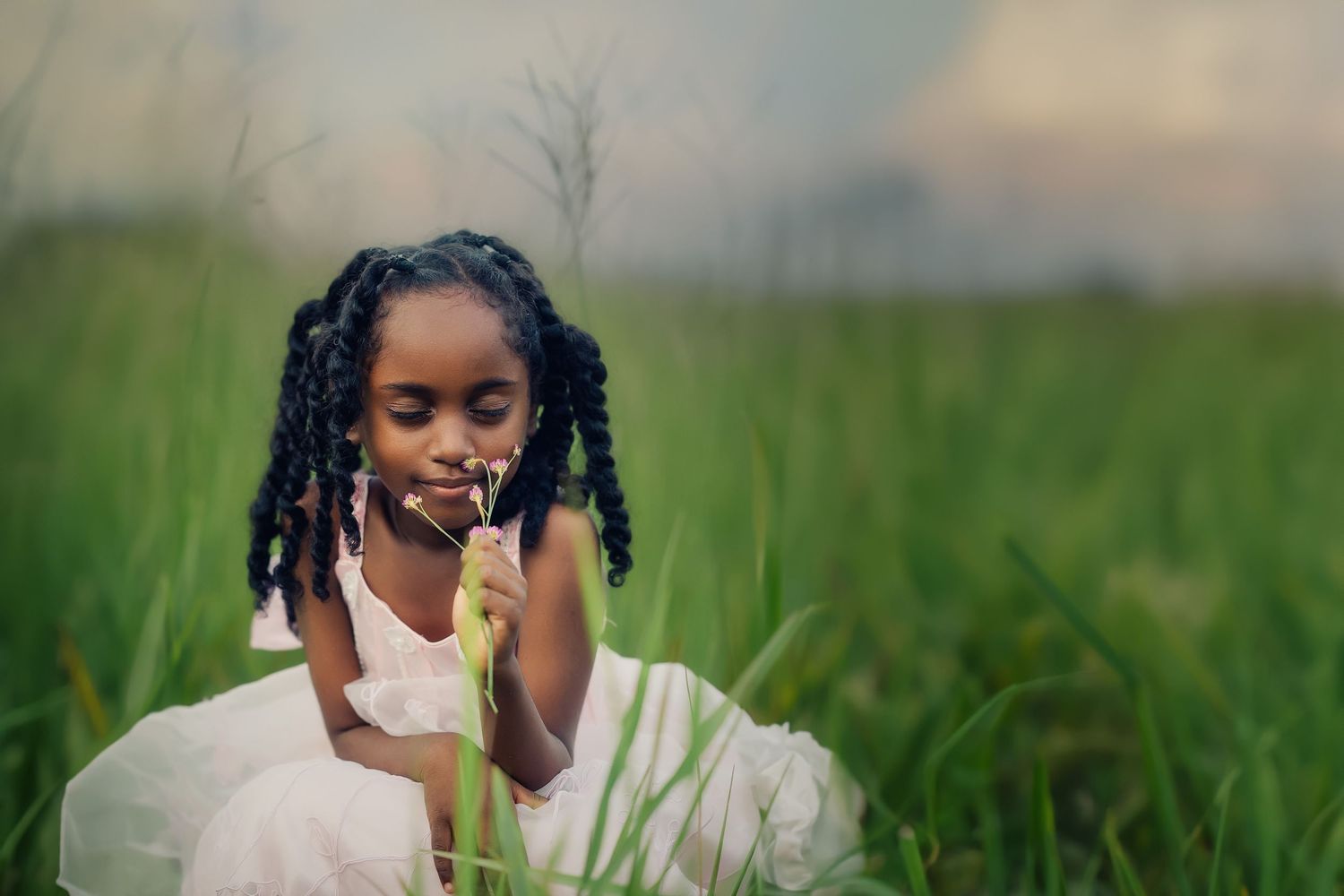 Person sitting in tall grass field during golden hour with soft natural lighting.