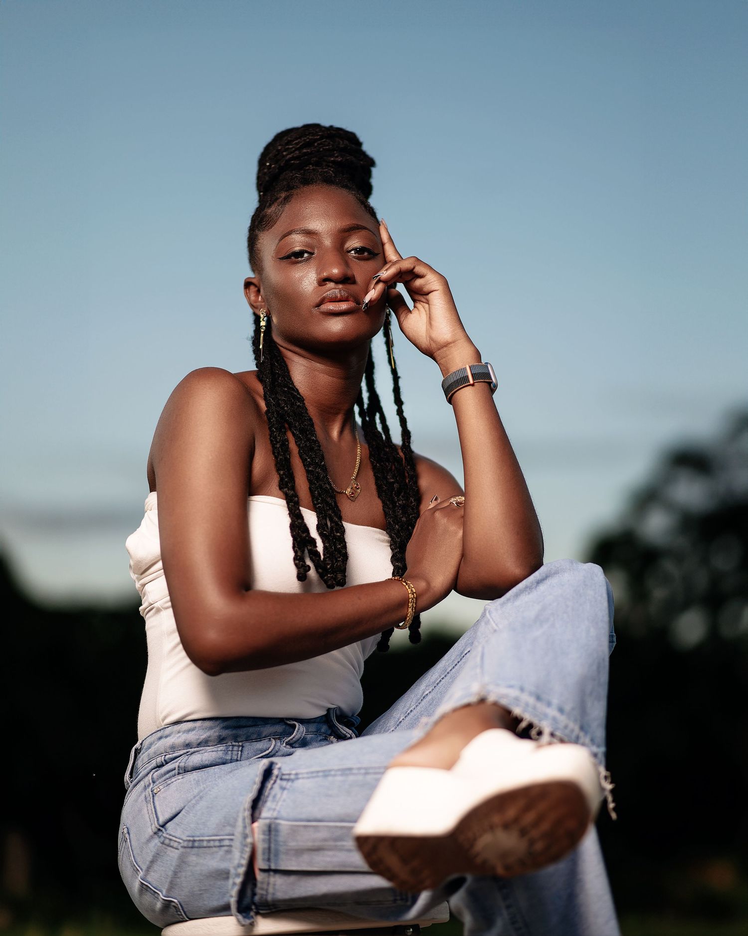 Sunset portrait in light colored top and denim against blue sky background.