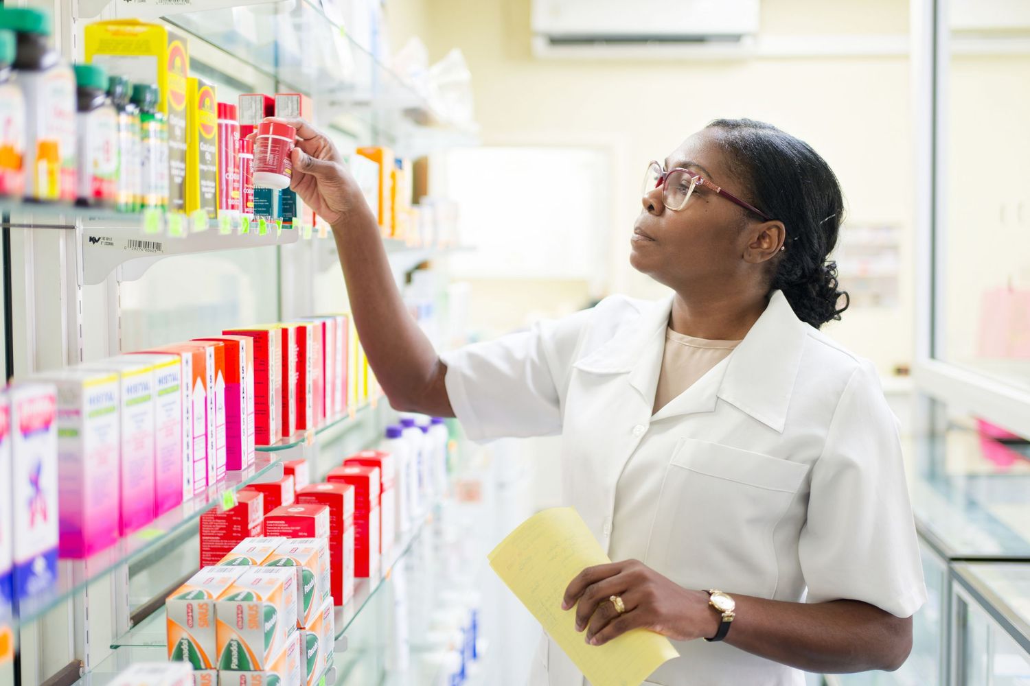 Pharmacists organizing medications and checking inventory on pharmacy shelves.