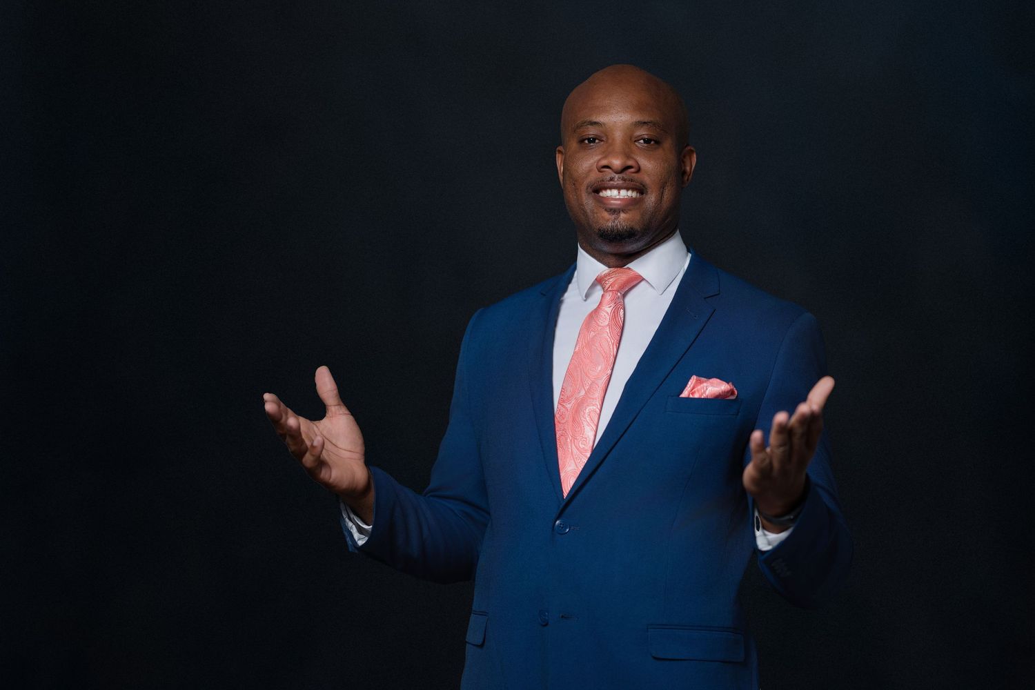 Professional portraits against dark background wearing navy blue suits.