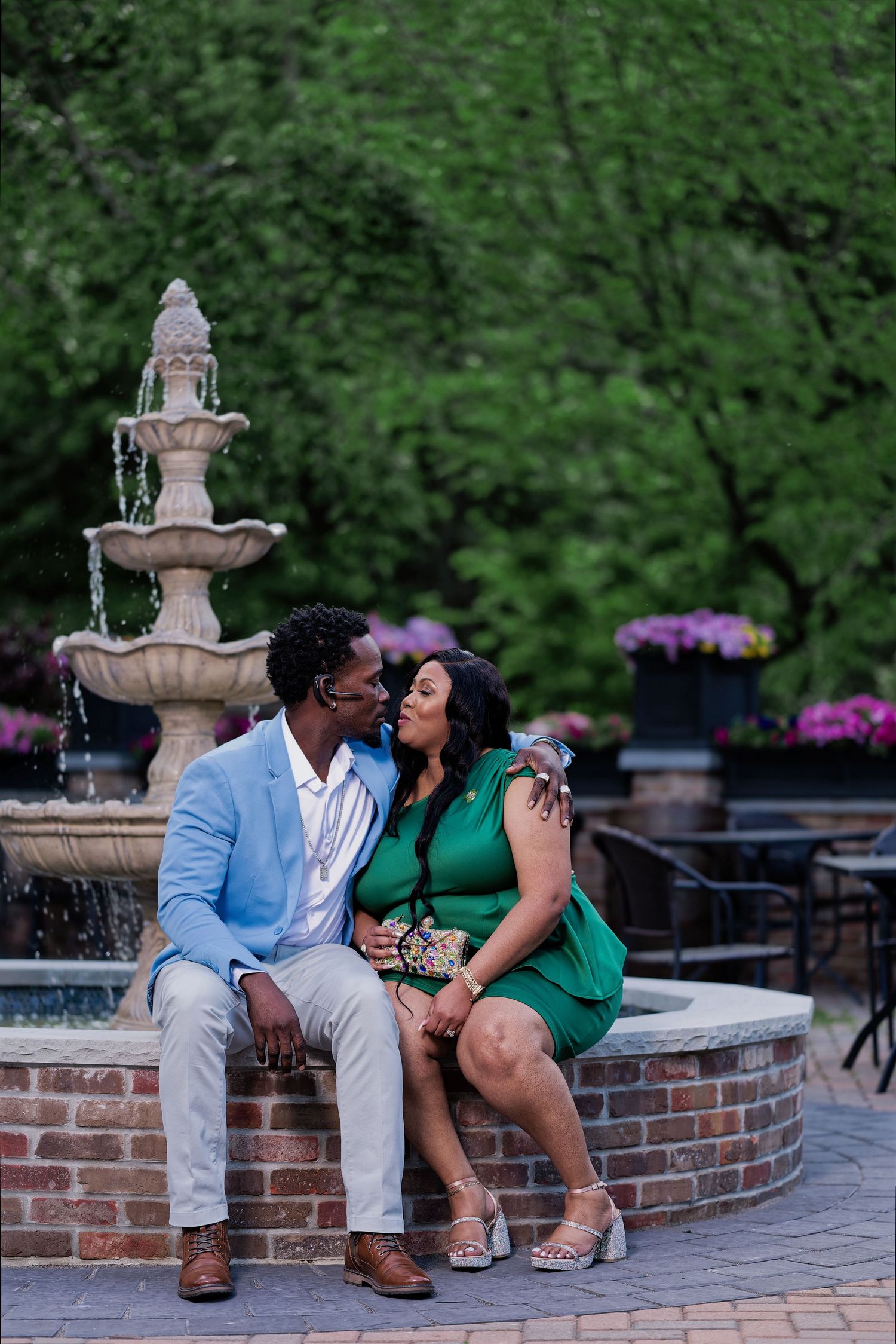 Couple sharing romantic moment by decorative fountain in outdoor garden setting.