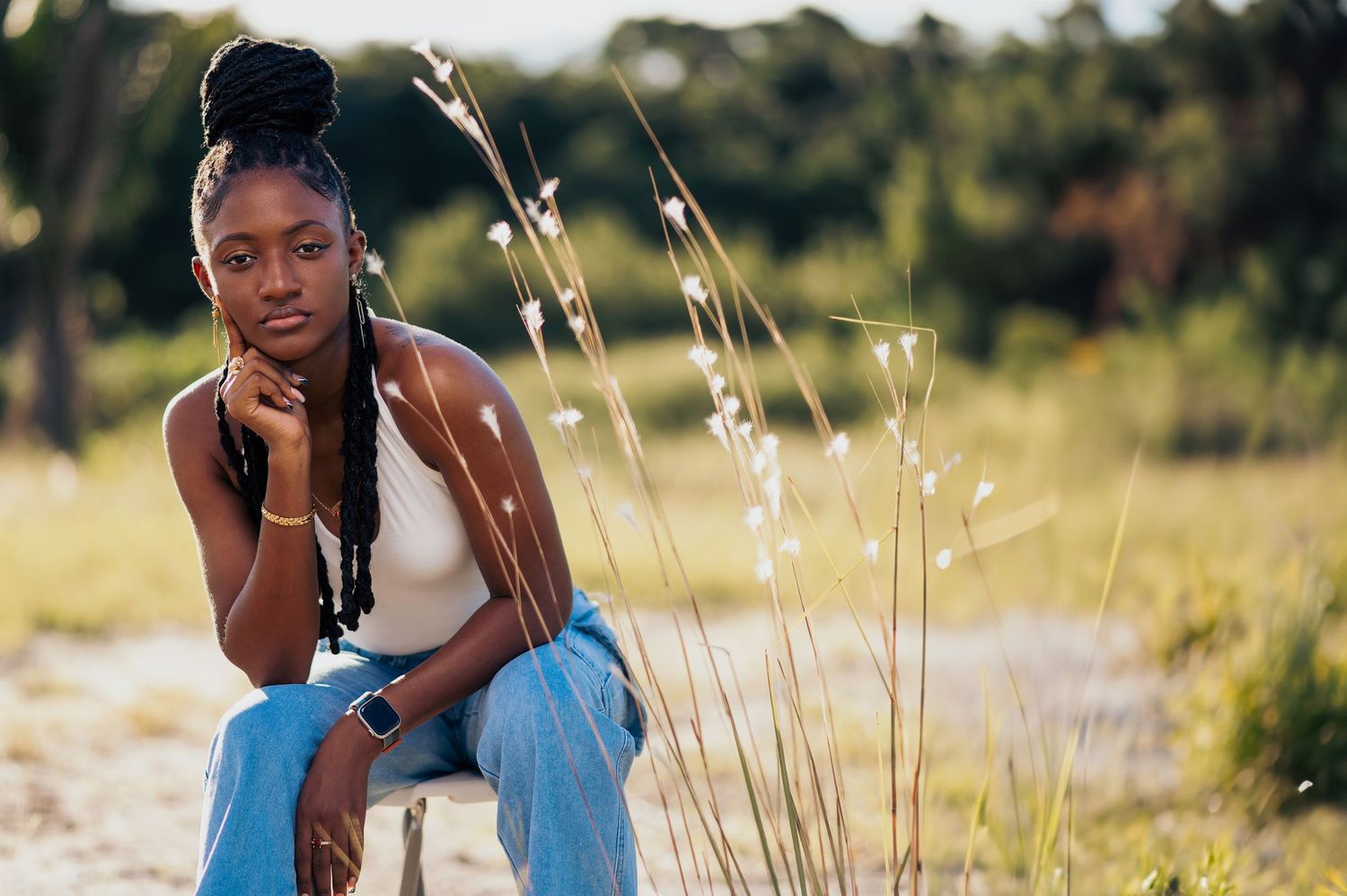 Natural light portrait in casual denim outfit posed among wild grass.
