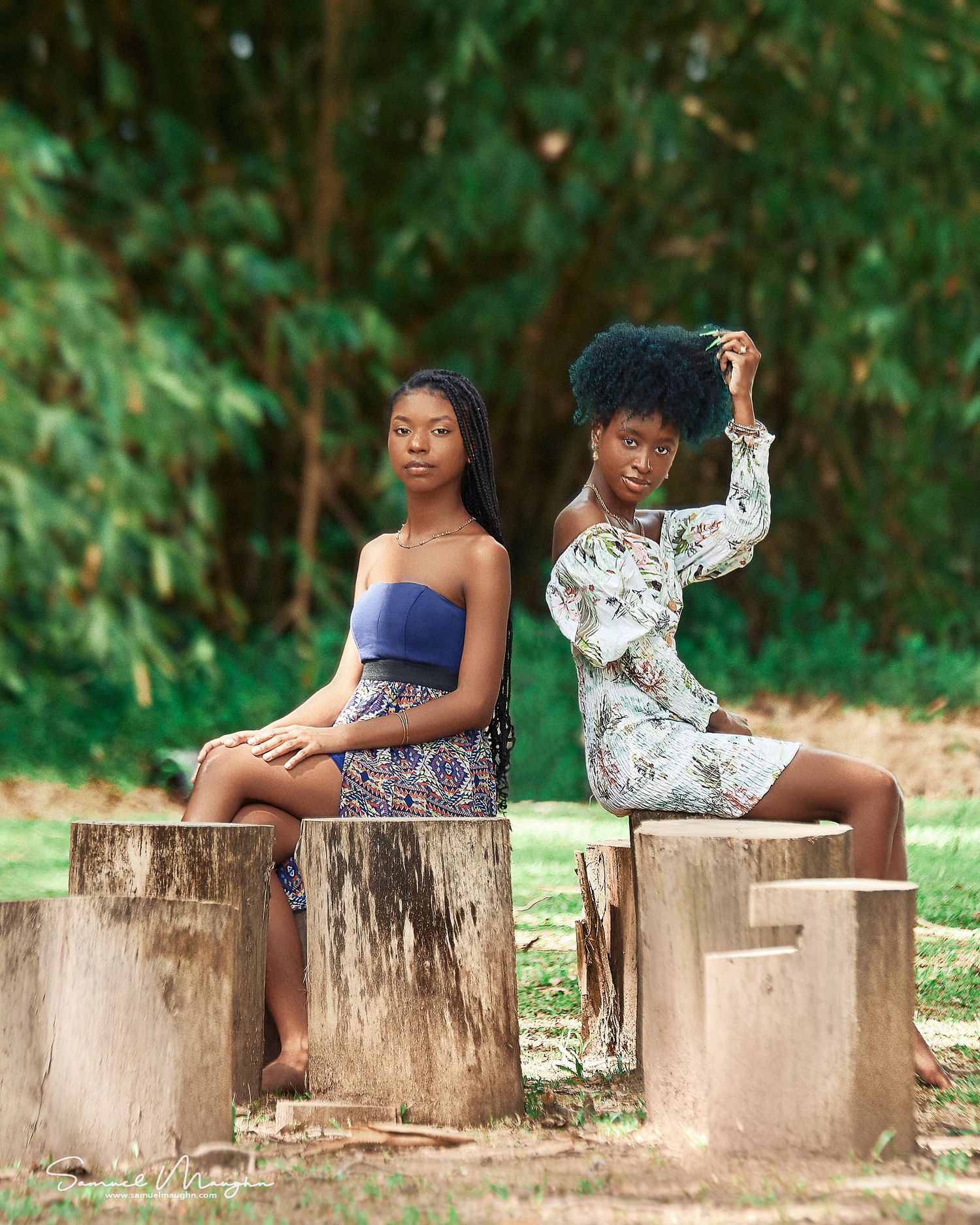 Creative portrait of two people sitting on wooden stumps in a garden setting.