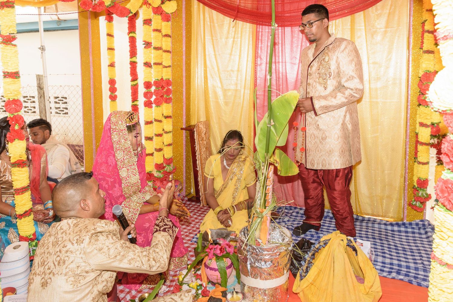 Traditional wedding ceremony setup with ornate gold and red decorations and fabric backdrops.