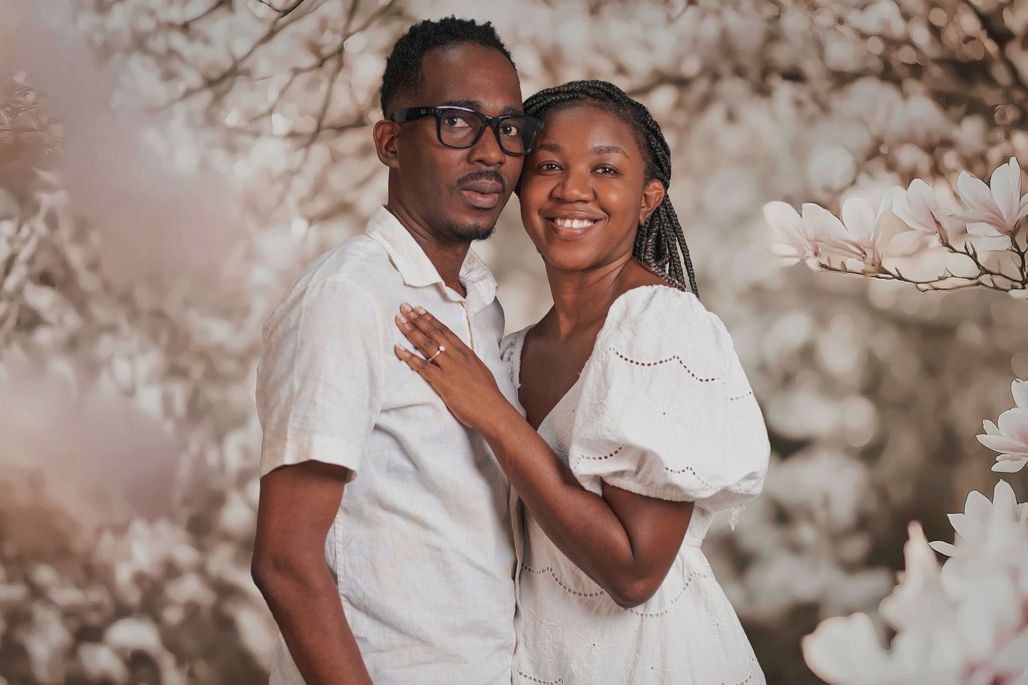 A couple in matching white outfits share a romantic moment outdoors with soft bokeh lighting and cherry blossoms.