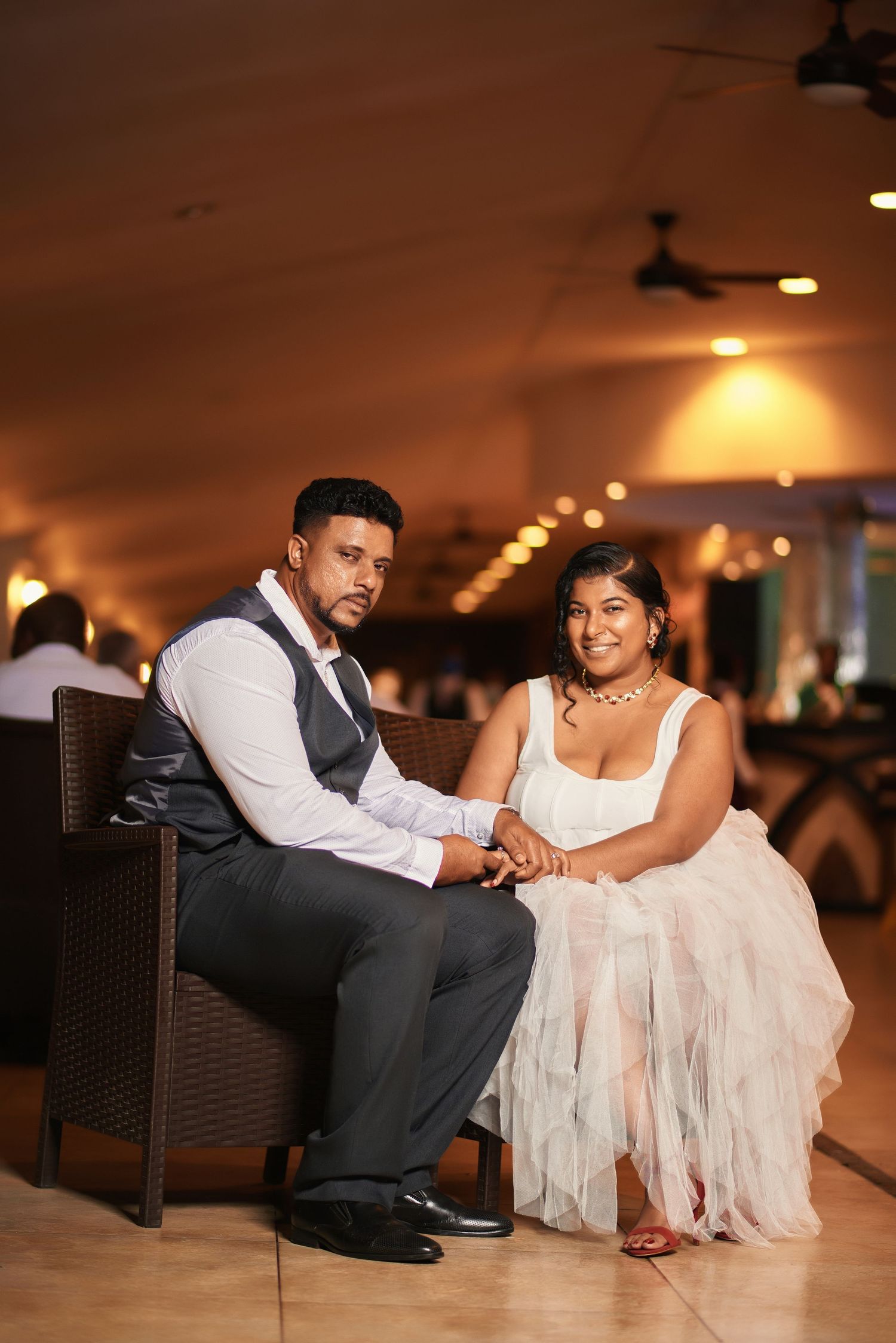 A couple shares an intimate moment while sitting together in an elegantly lit indoor setting.