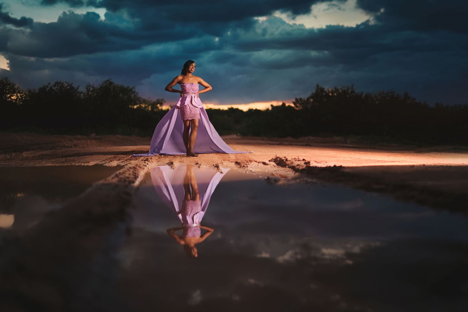 Dramatic silhouette of flowing purple dress against moody sunset backdrop.