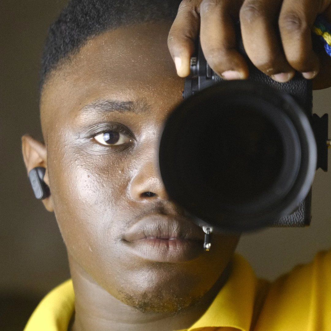 Close-up shot of someone holding a camera lens against a dark background.
