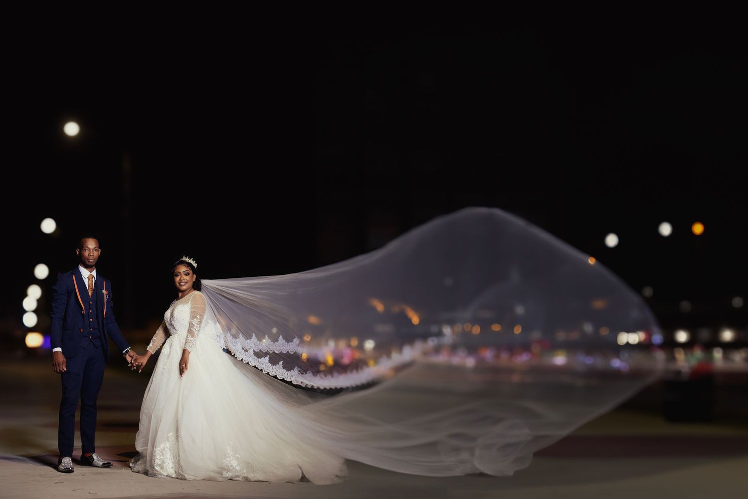Romantic nighttime wedding portrait with city lights twinkling in the background.