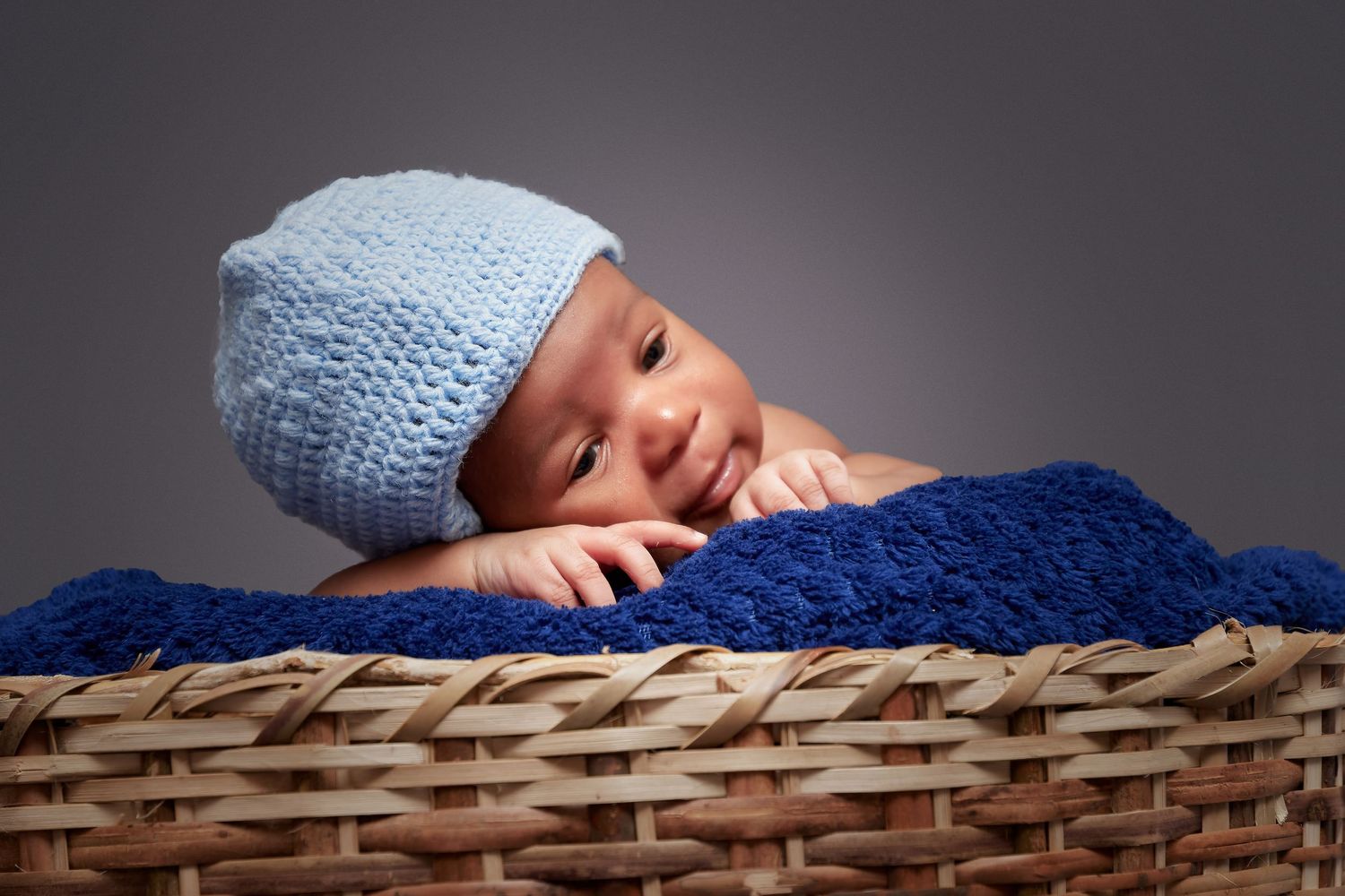 Newborn baby sleeping peacefully in woven basket with floral decorations.