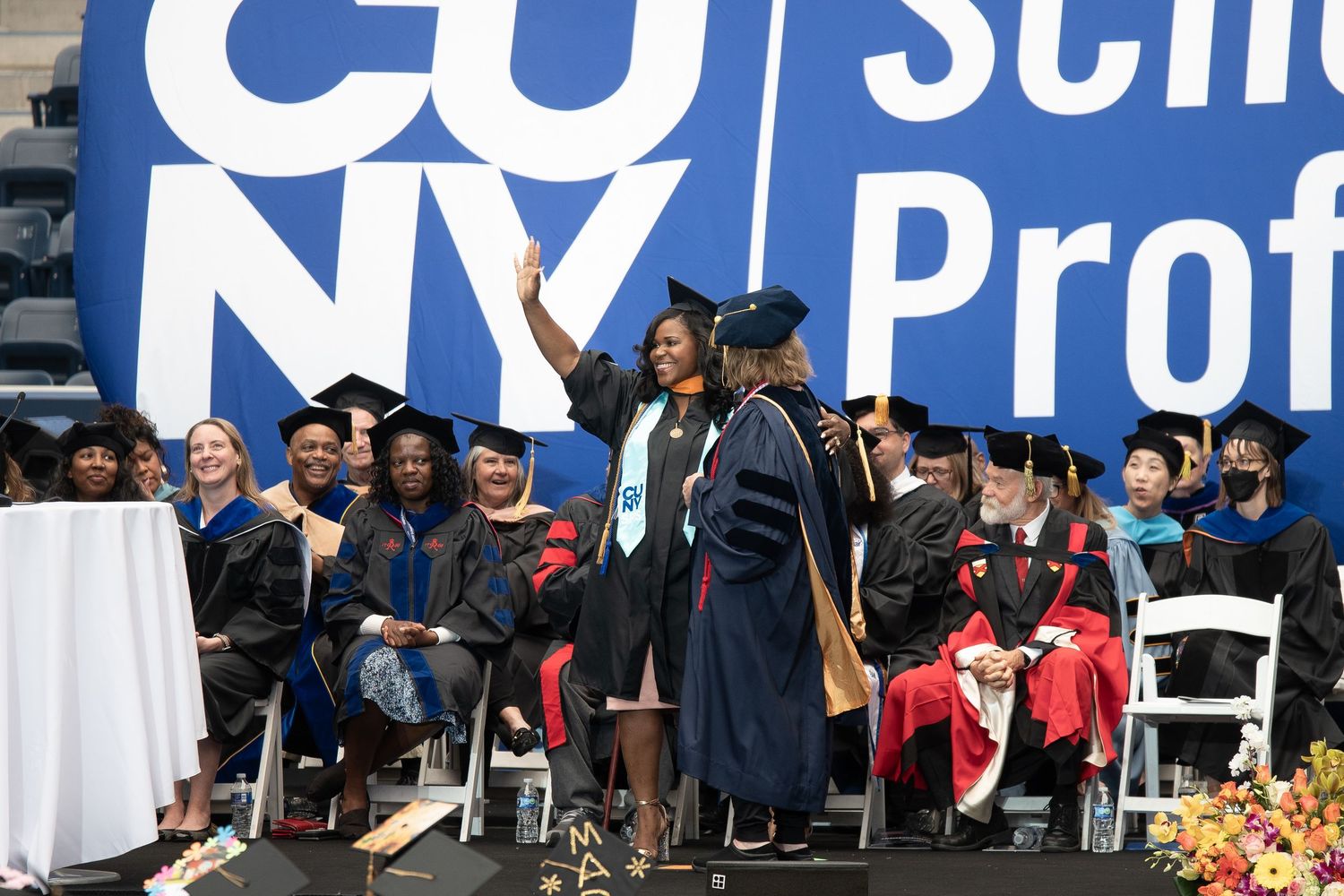 Large outdoor event with blue banners and white chairs set up for graduation ceremony.