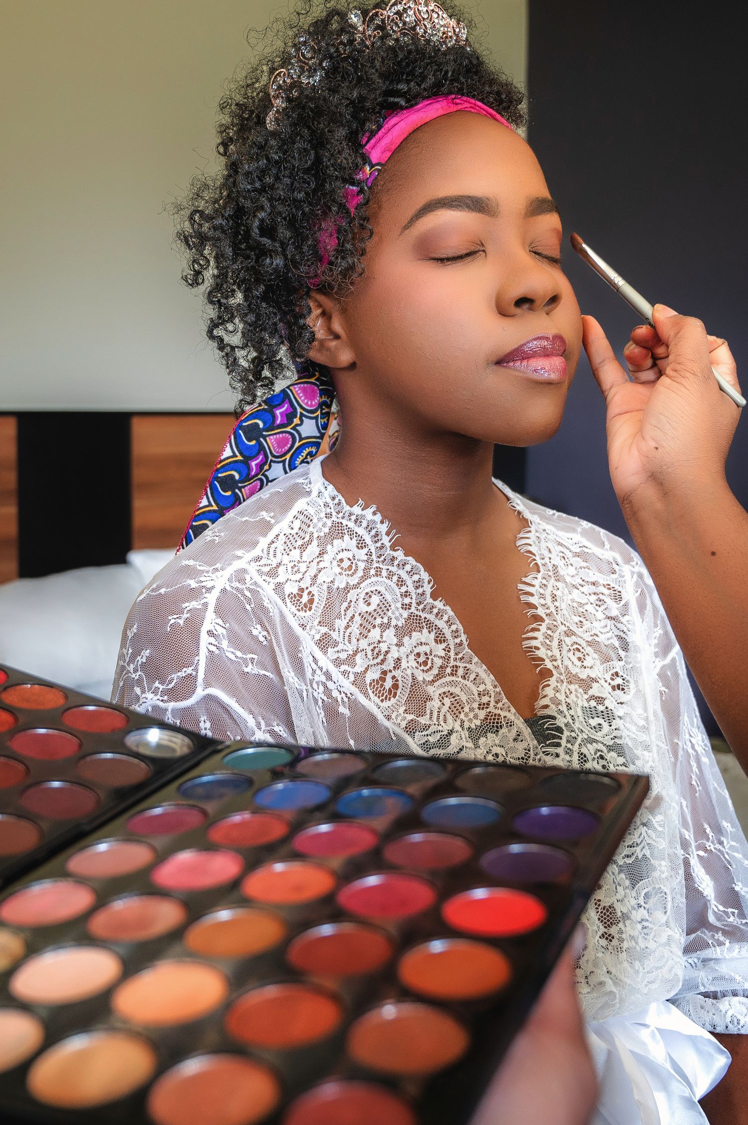 Professional makeup application with colorful eyeshadow palette in frame.