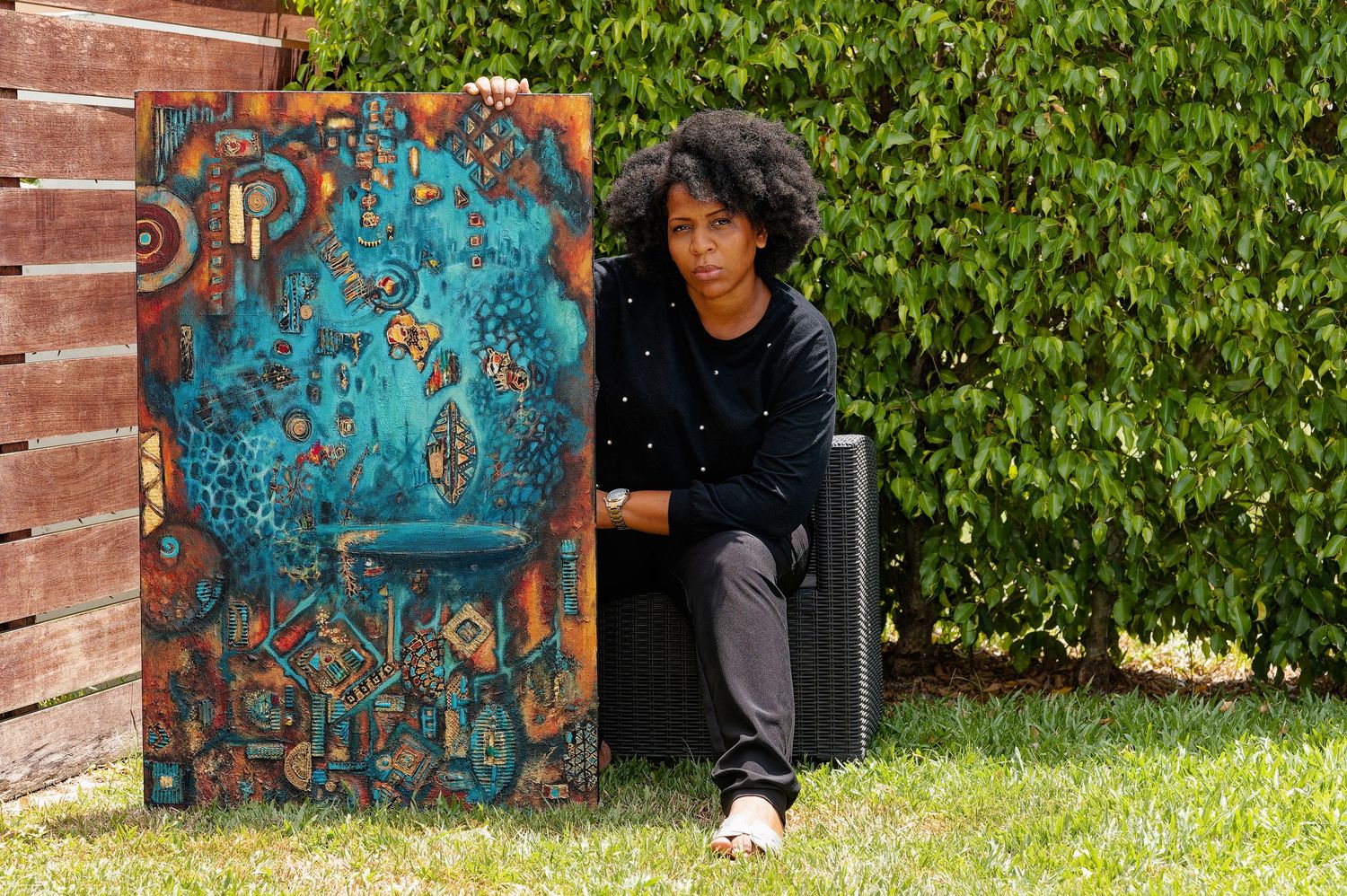 Creative pose by a brick wall with blue graffiti art and green foliage.