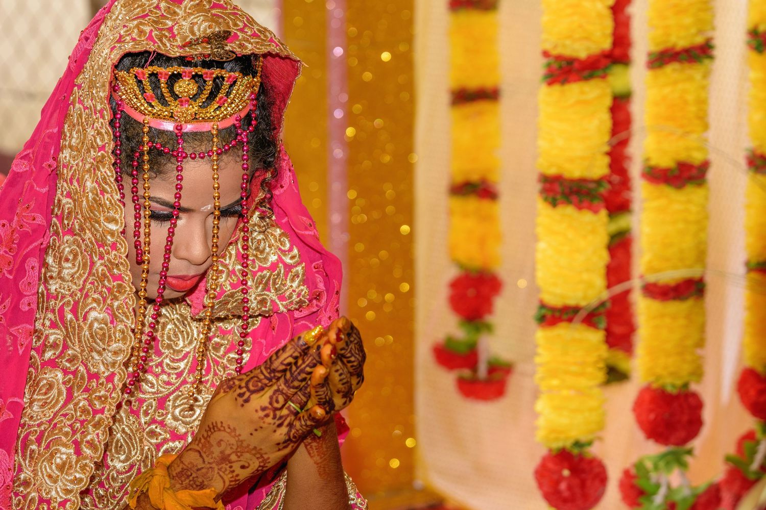 Traditional wedding decor featuring floral garlands and gold accents against warm lighting.