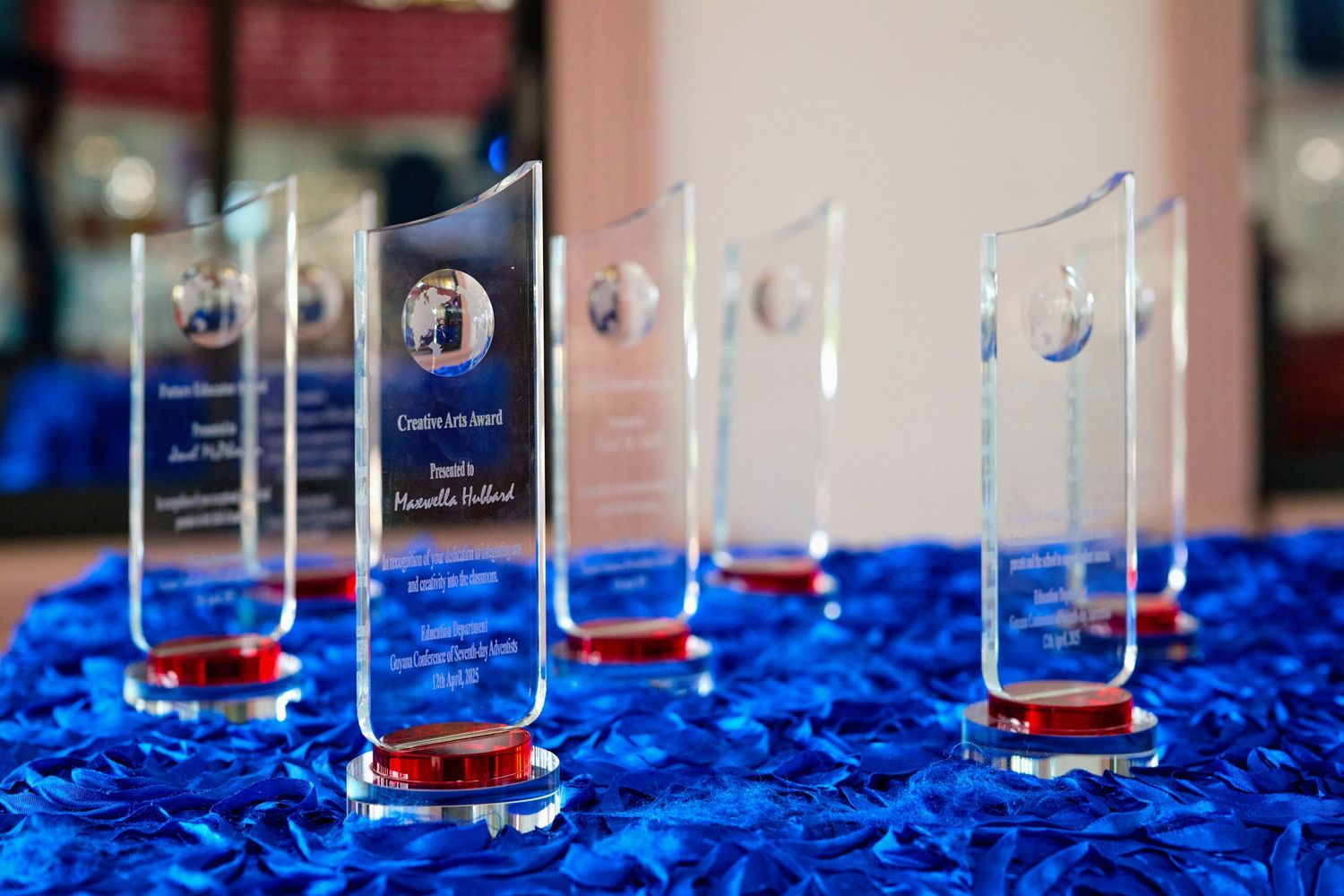 Close-up of transparent acrylic awards arranged in line on blue textured surface.