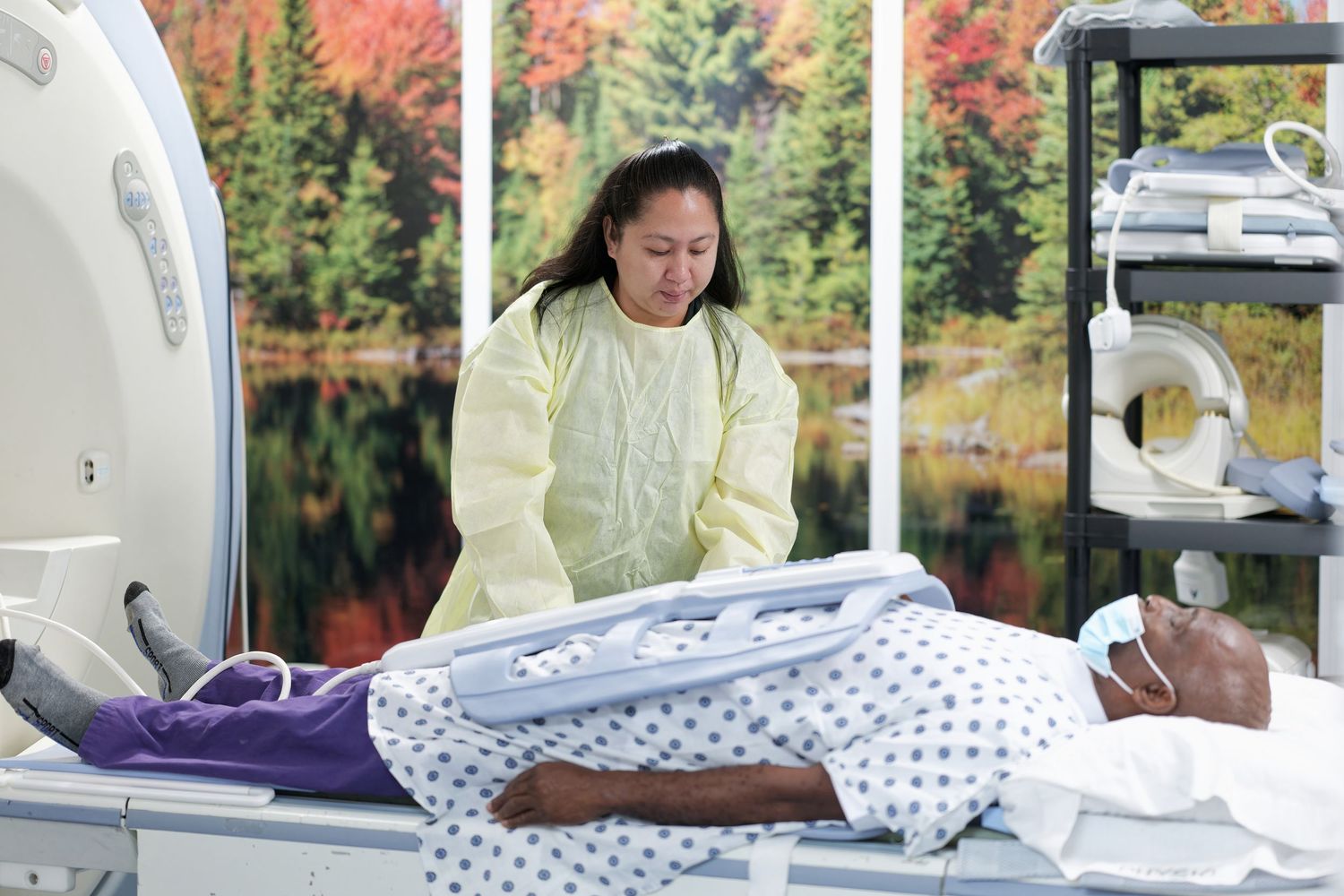 Medical staff providing patient care in hospital beds with autumn scenery visible through windows.