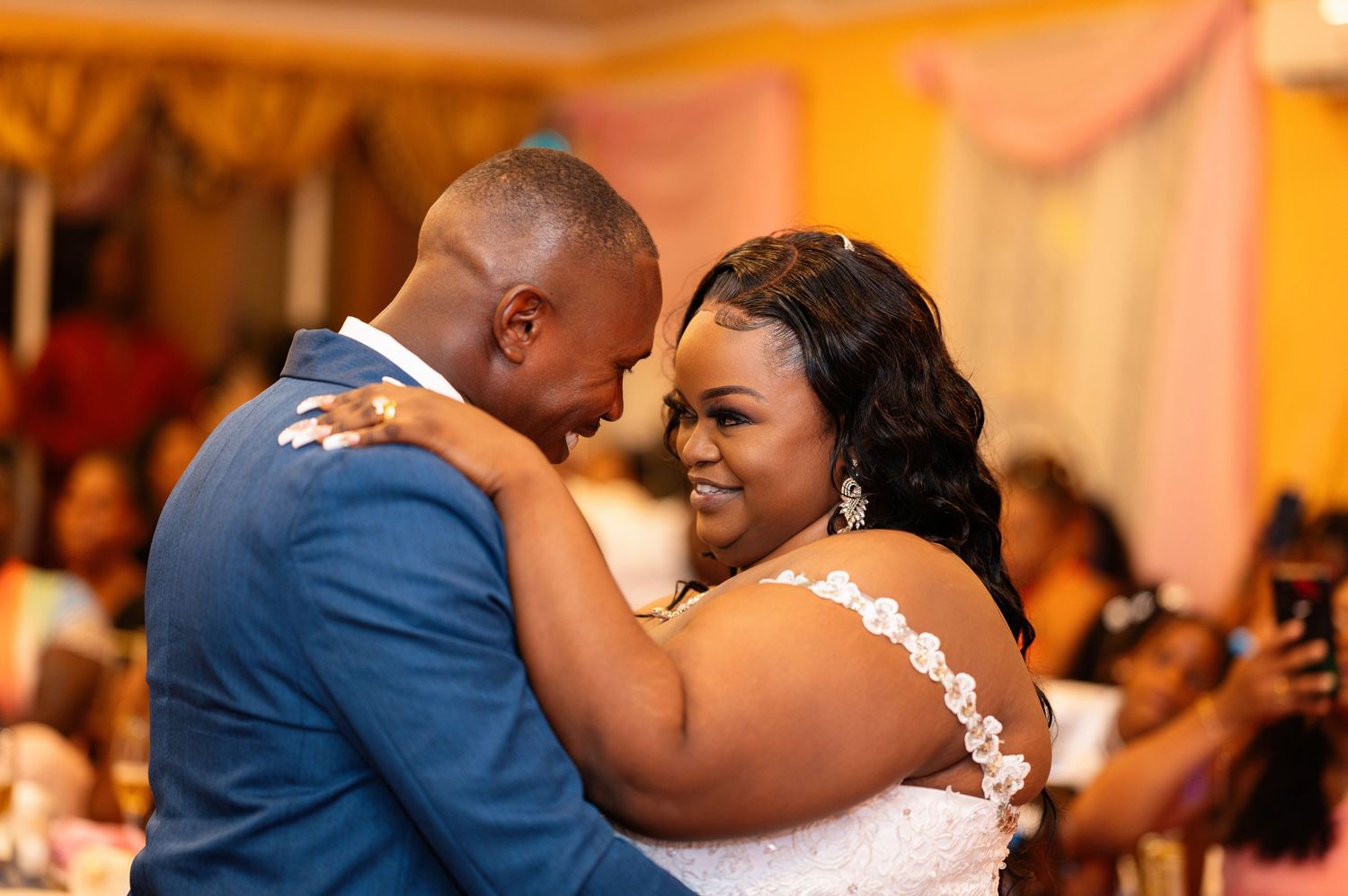 Bride and groom share an intimate first dance at their wedding reception, smiling joyfully together.