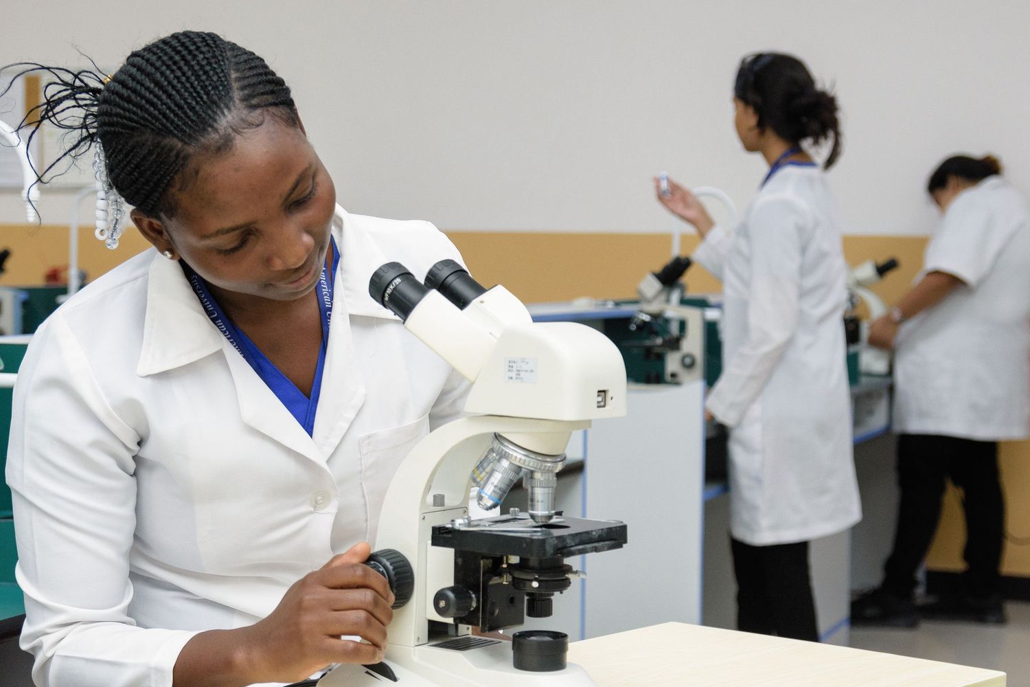 Researchers using microscopes and lab equipment in modern laboratory setting.