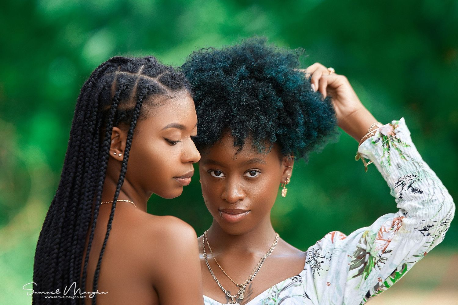 Intimate portrait session with two people against vibrant green foliage background.
