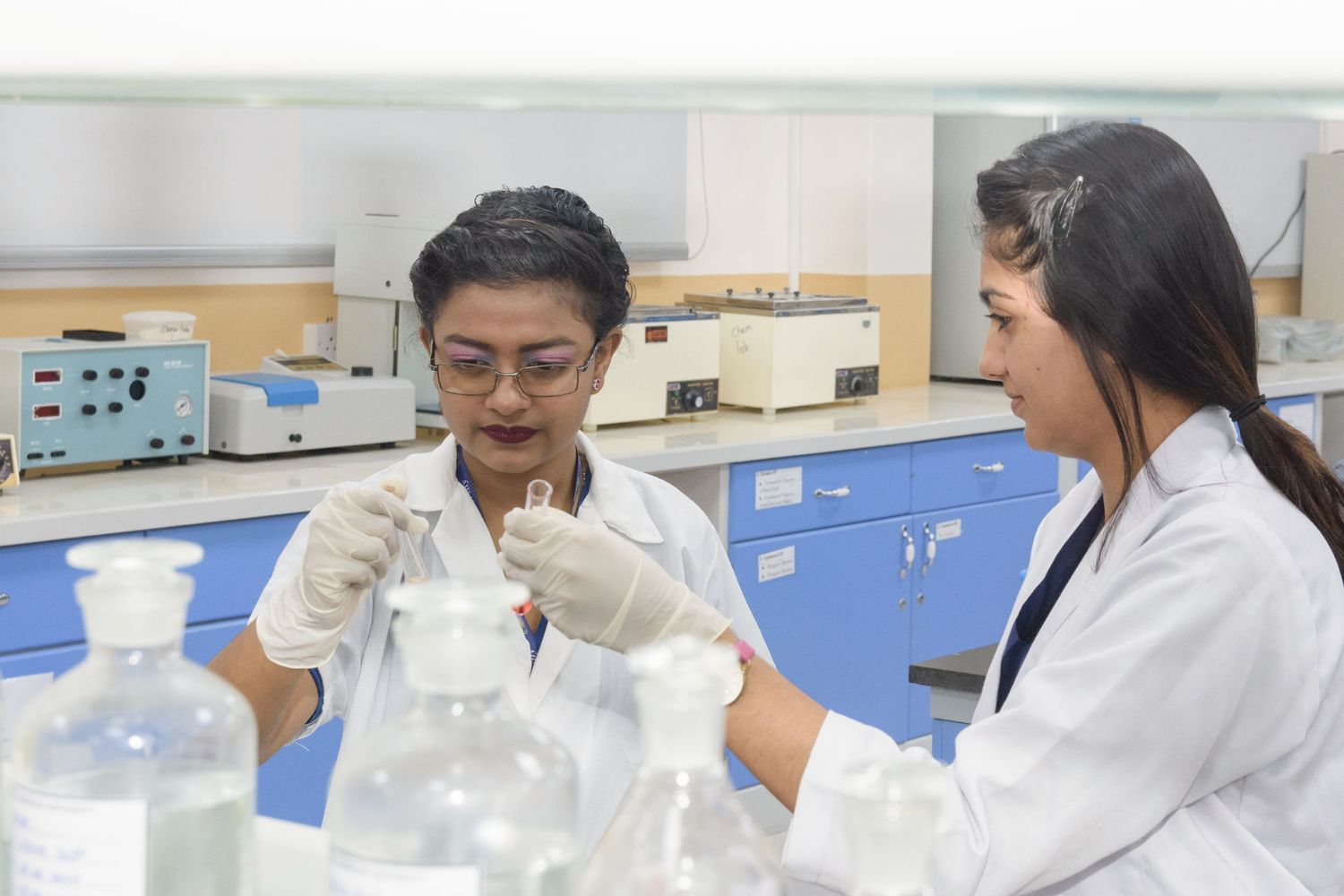 Laboratory professionals performing chemical analysis with test tubes and lab equipment.