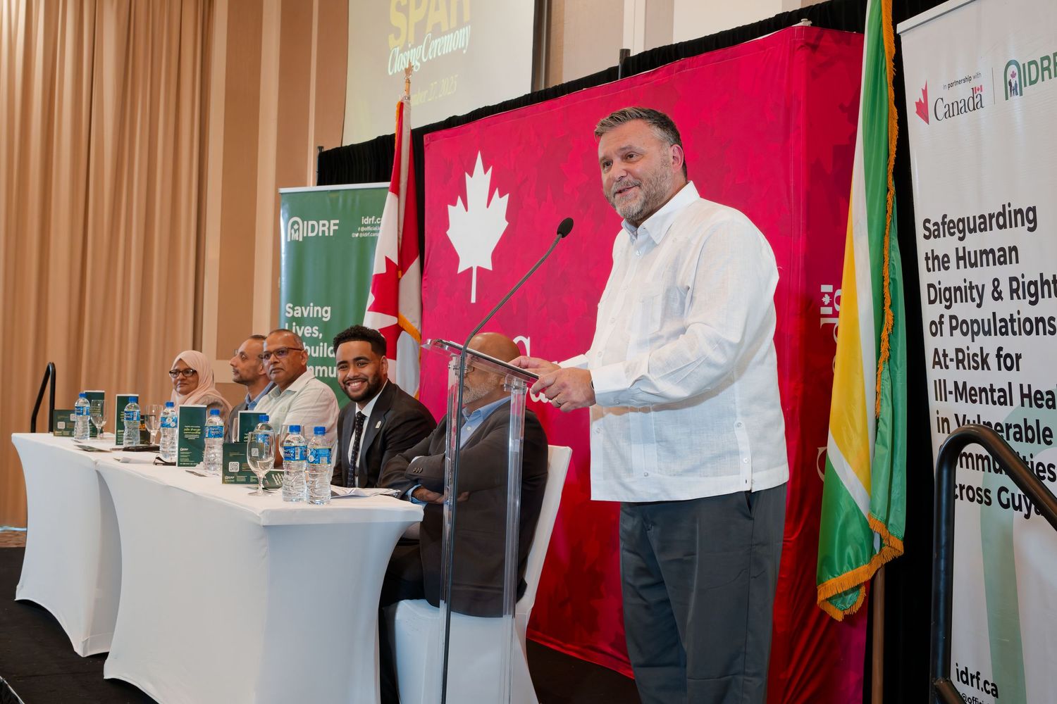A speaker presents at a panel discussion on safeguarding human dignity and rights for mental health populations in Guyana.