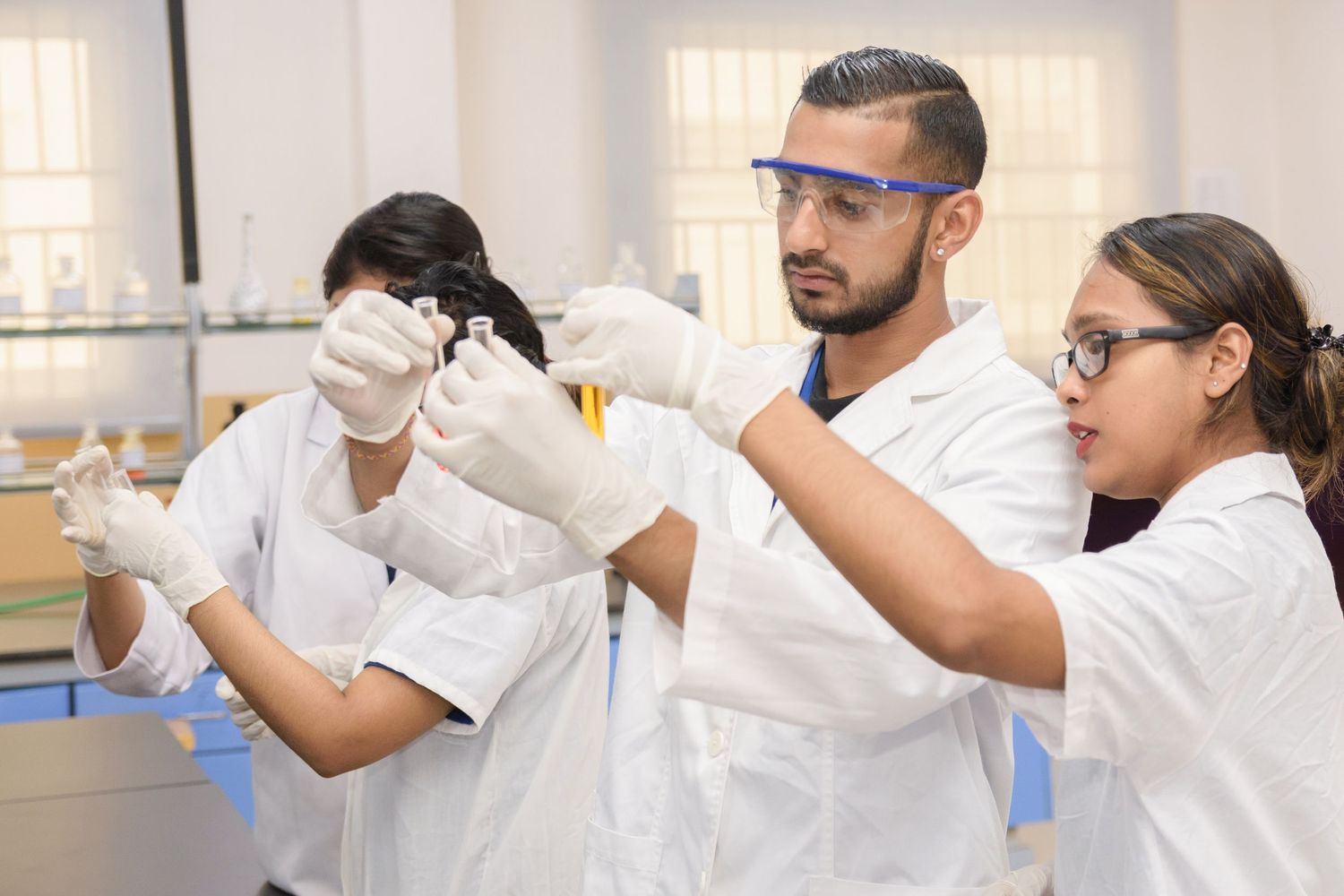 Research team examining specimens and taking notes in a well-equipped laboratory environment.